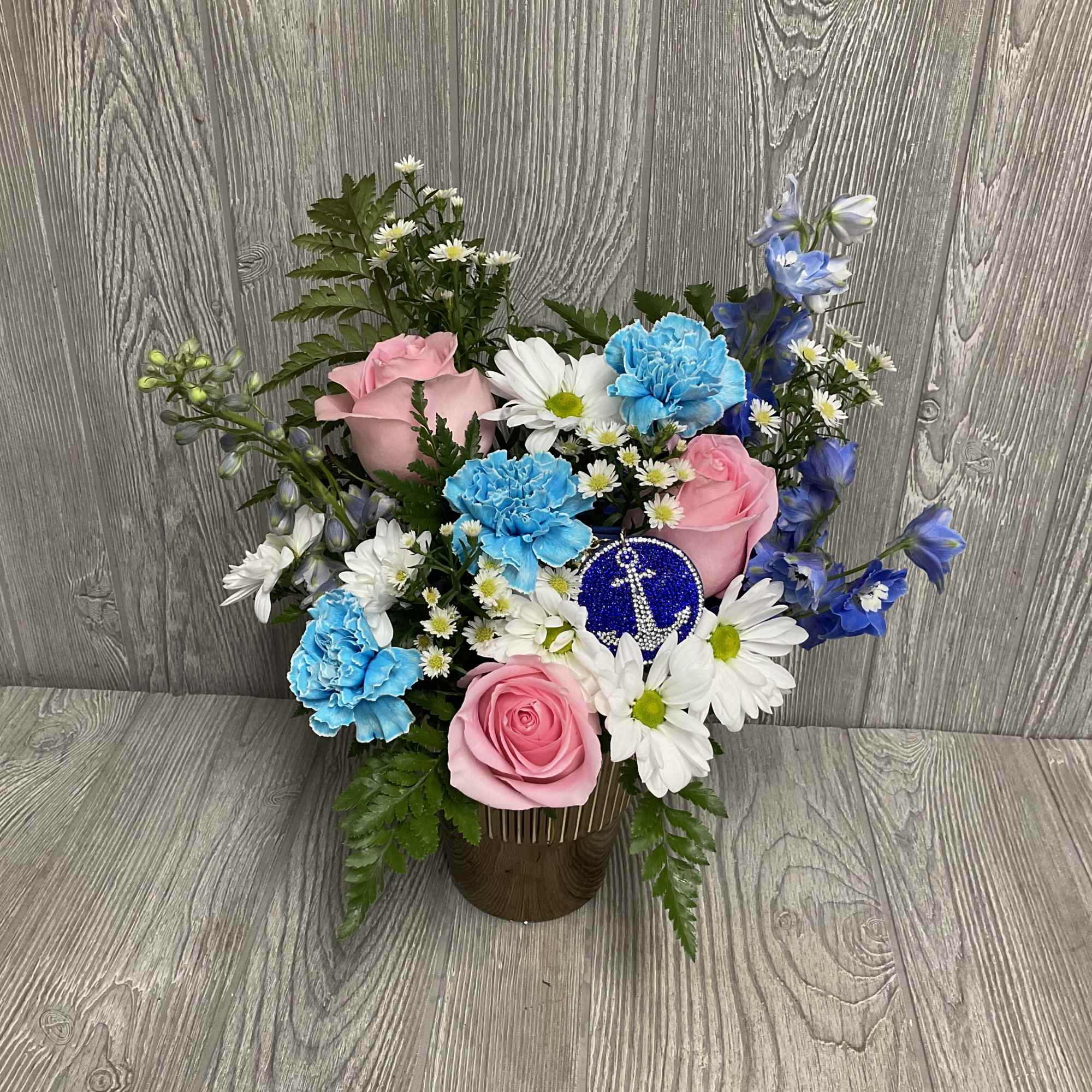 Pink roses and blue carnations arranged with white daisies in a vase