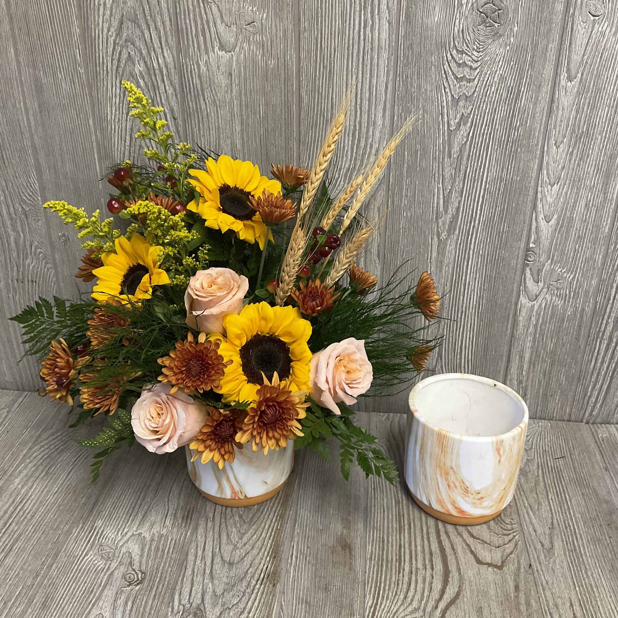 Sunflower and rose arrangement in a marbled ceramic vase