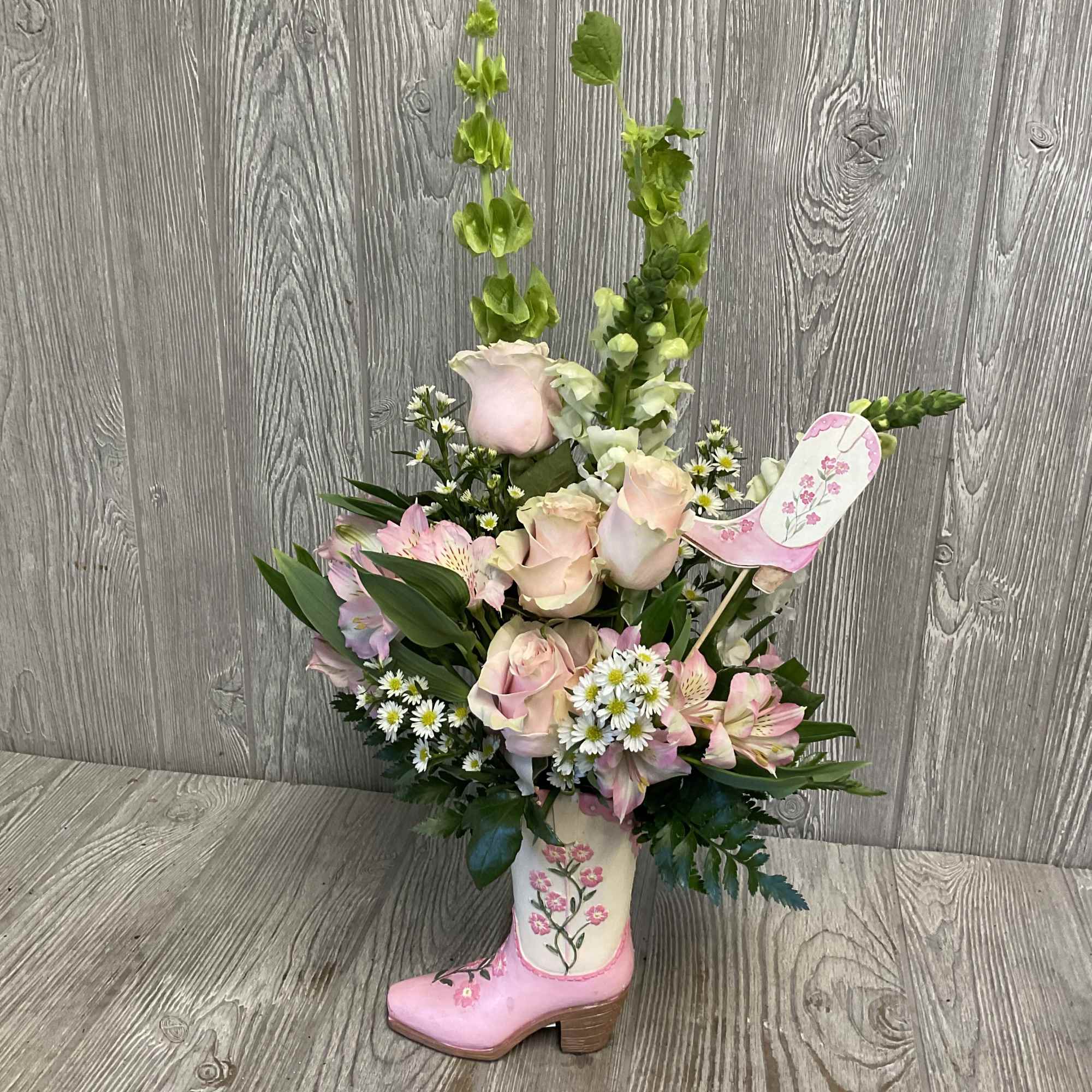 Pink roses and mixed flowers arranged in a decorative boot vase