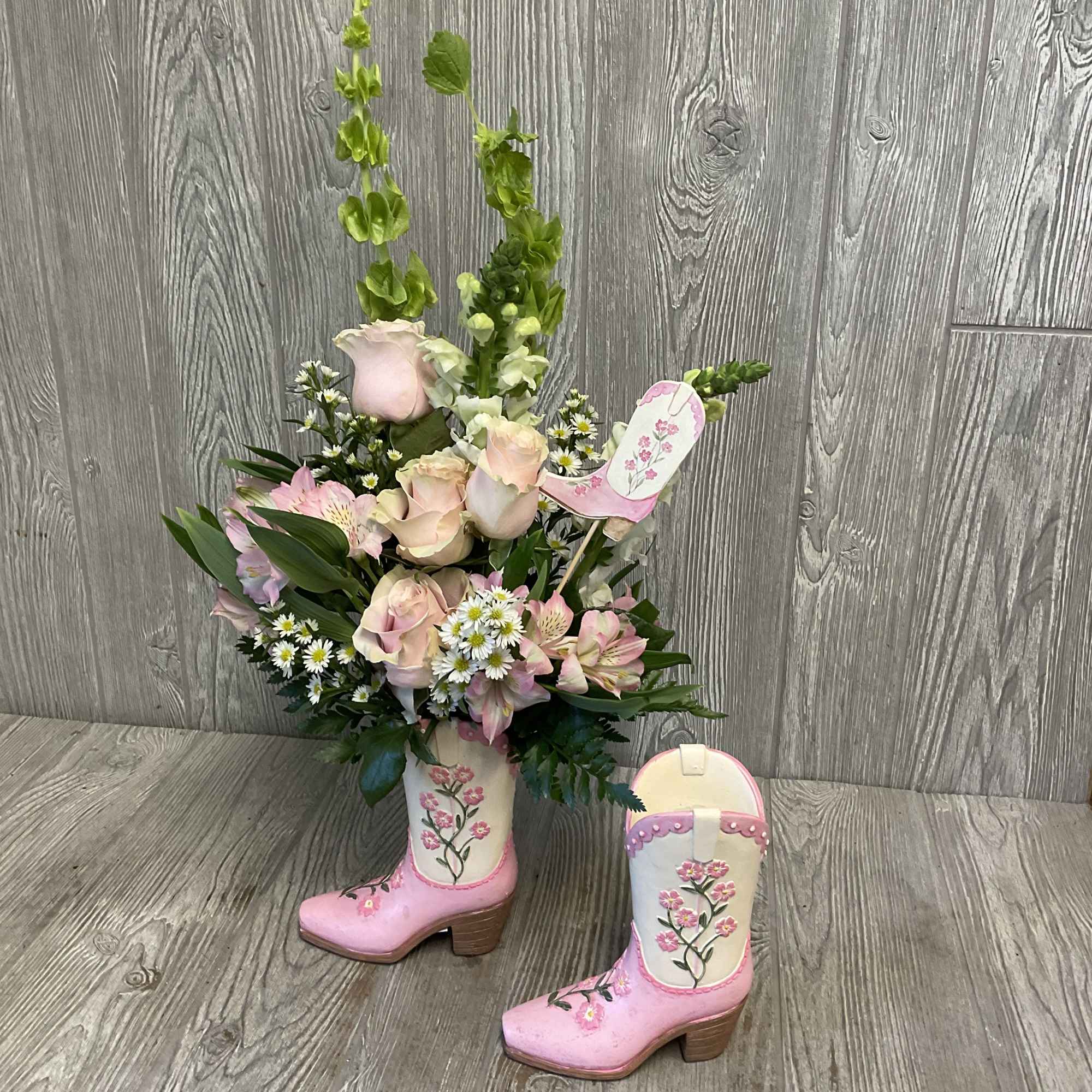 Pink and cream floral arrangement in painted cowboy boots