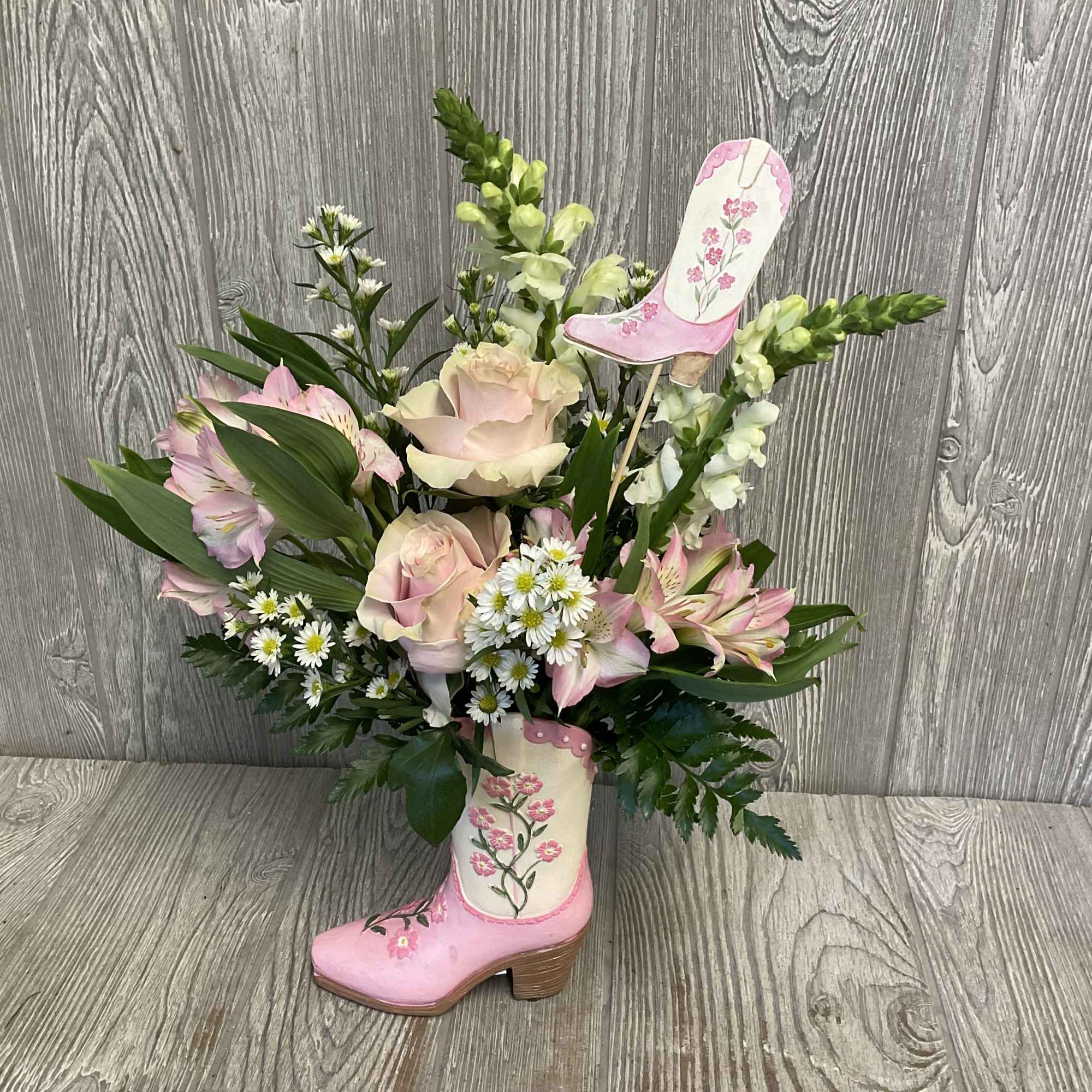 Pink roses and lilies arranged in a decorative boot vase