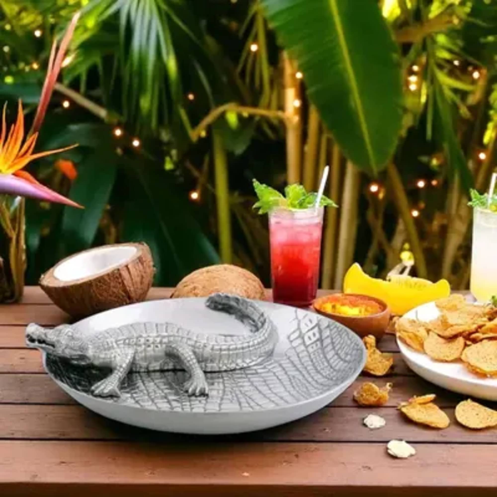 Decorative crocodile dish on a table with tropical drinks and snacks