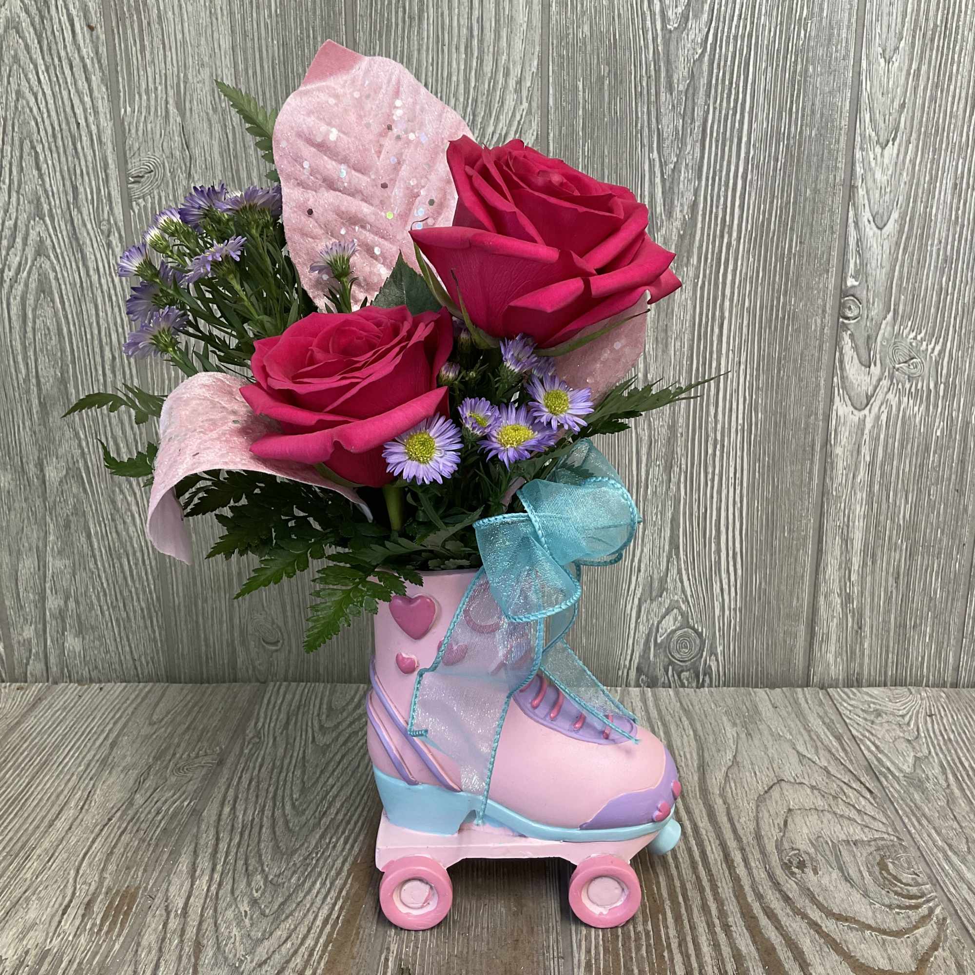 Pink roses and purple daisies arranged in a pink roller skate container