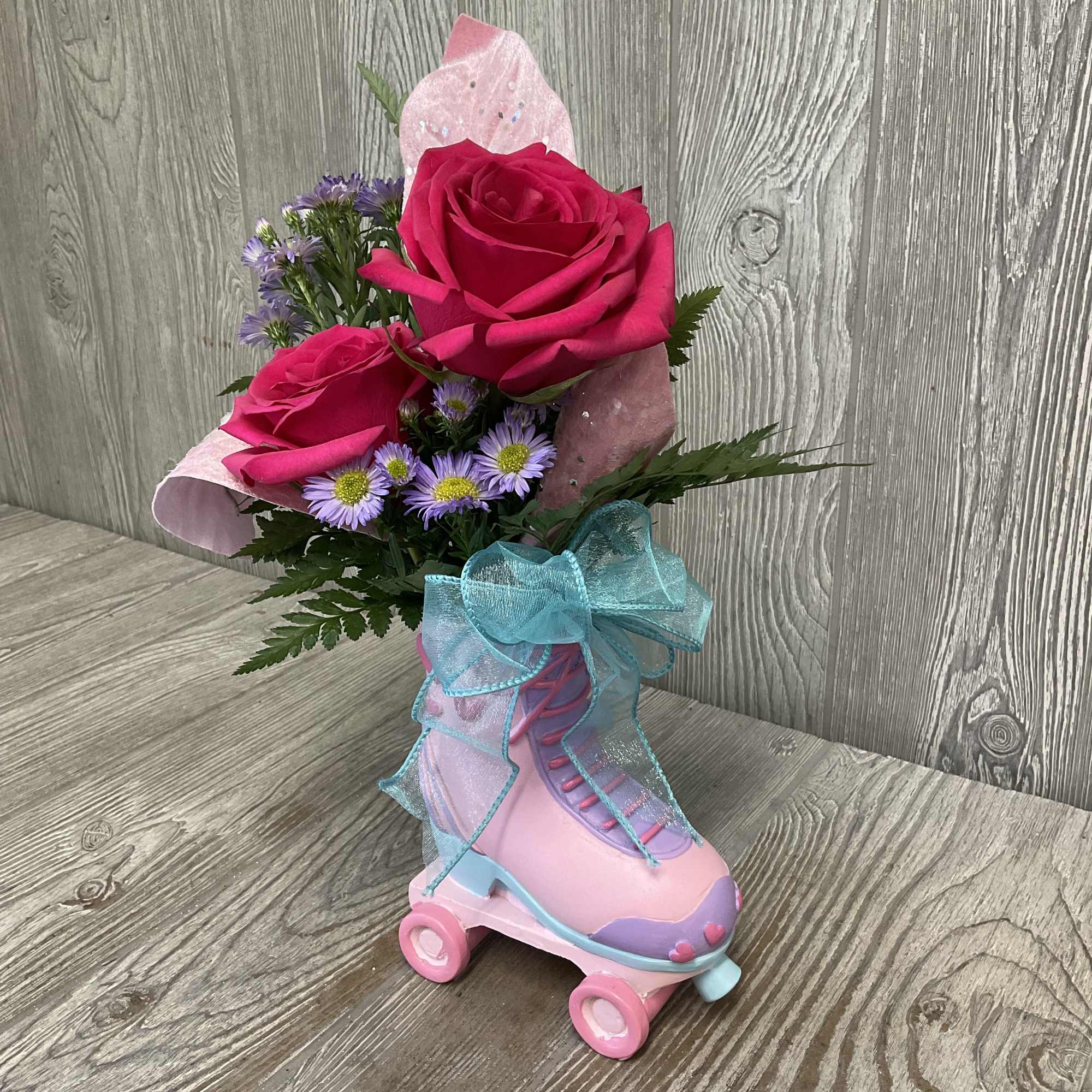 Pink roses and purple daisies arranged in a roller skate container
