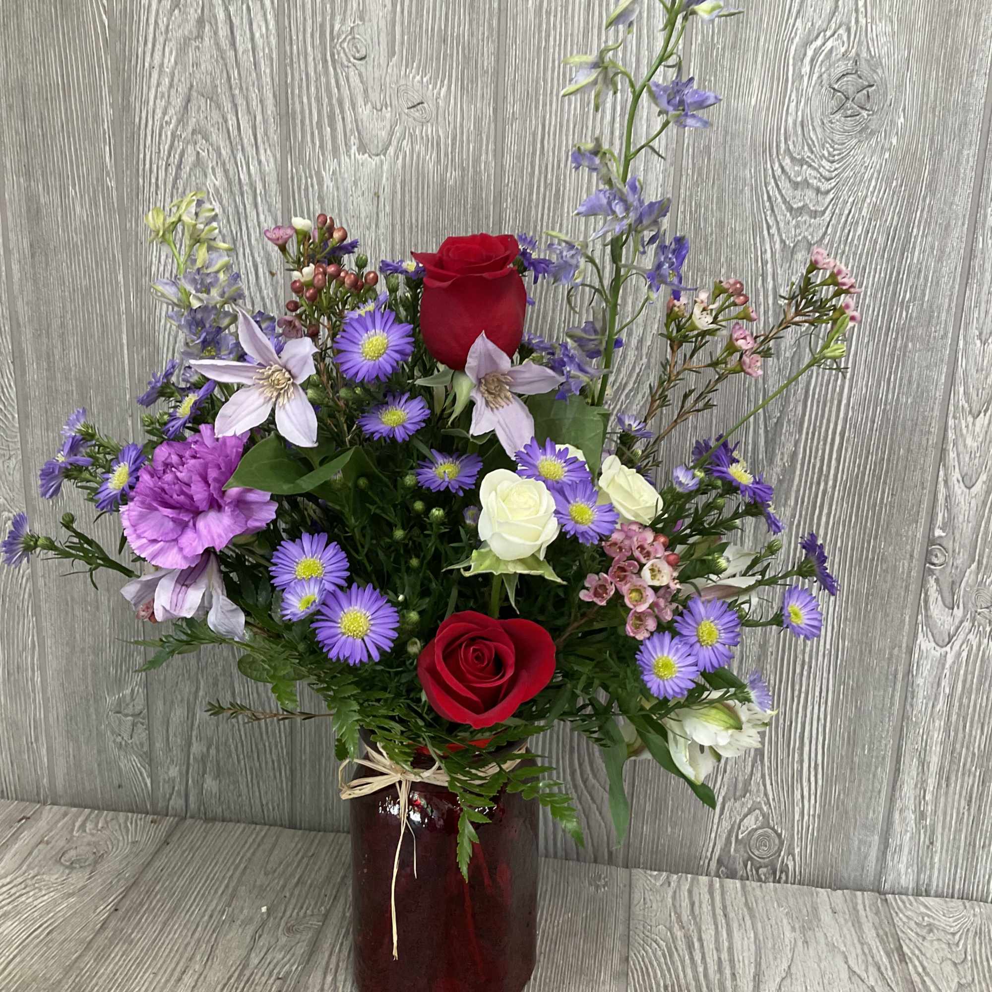 Romantic arrangement of wild flowers in a red vase.