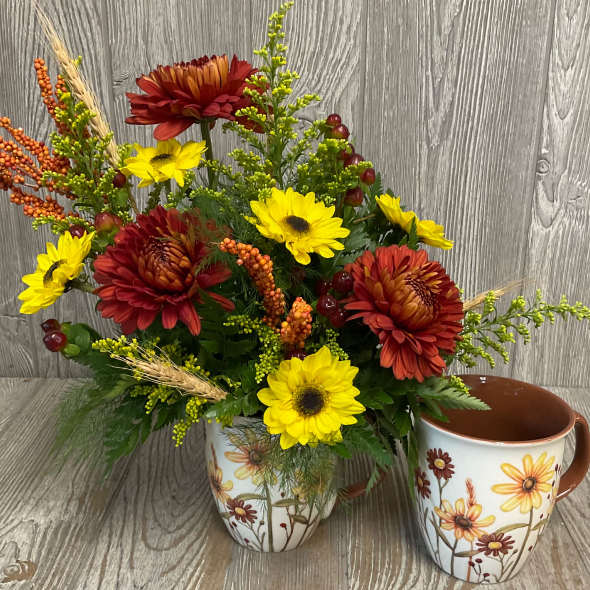 Fall floral arrangement in a floral ceramic mug beside a matching cup