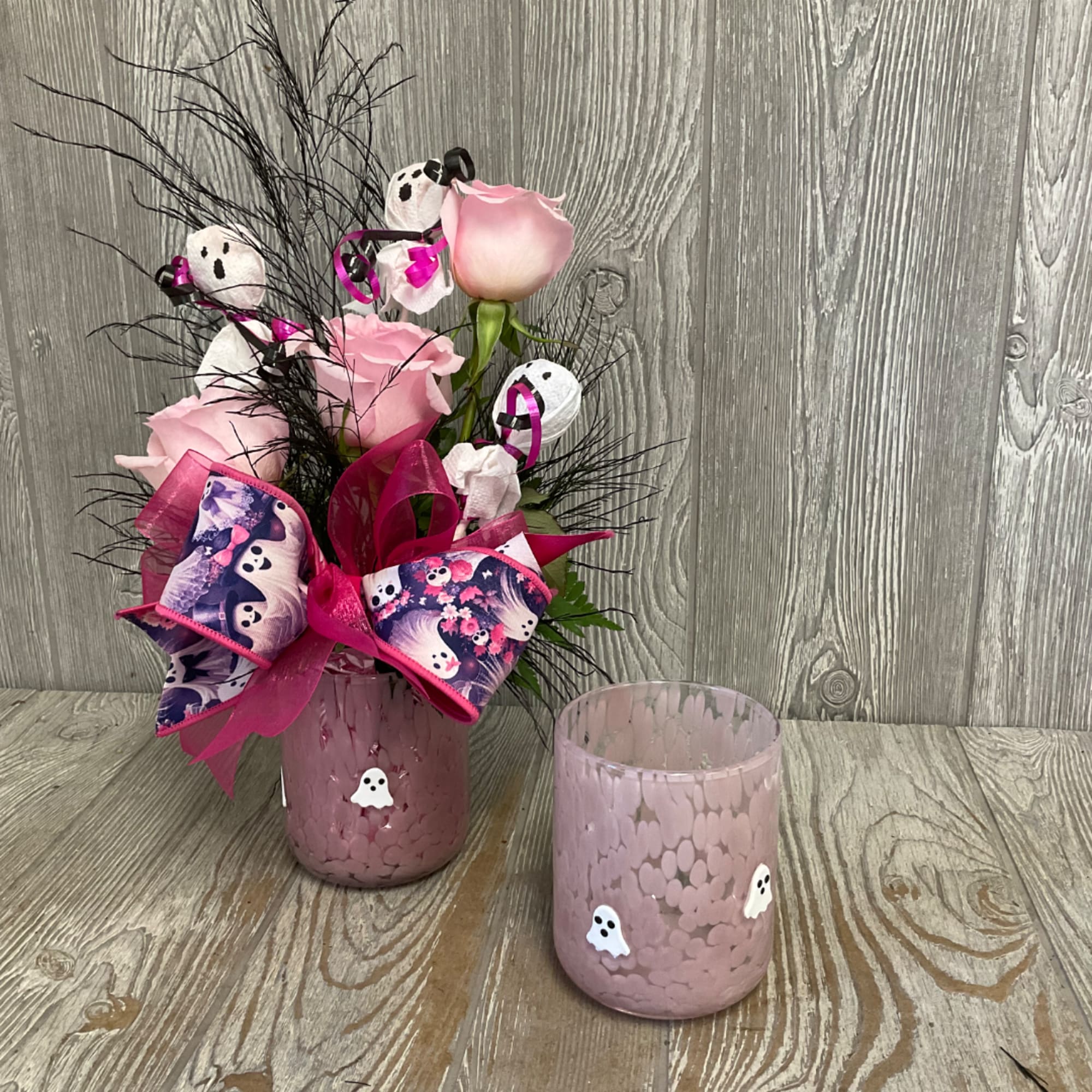Pink roses in a pink glass vase with Halloween ribbon and ghost decorations