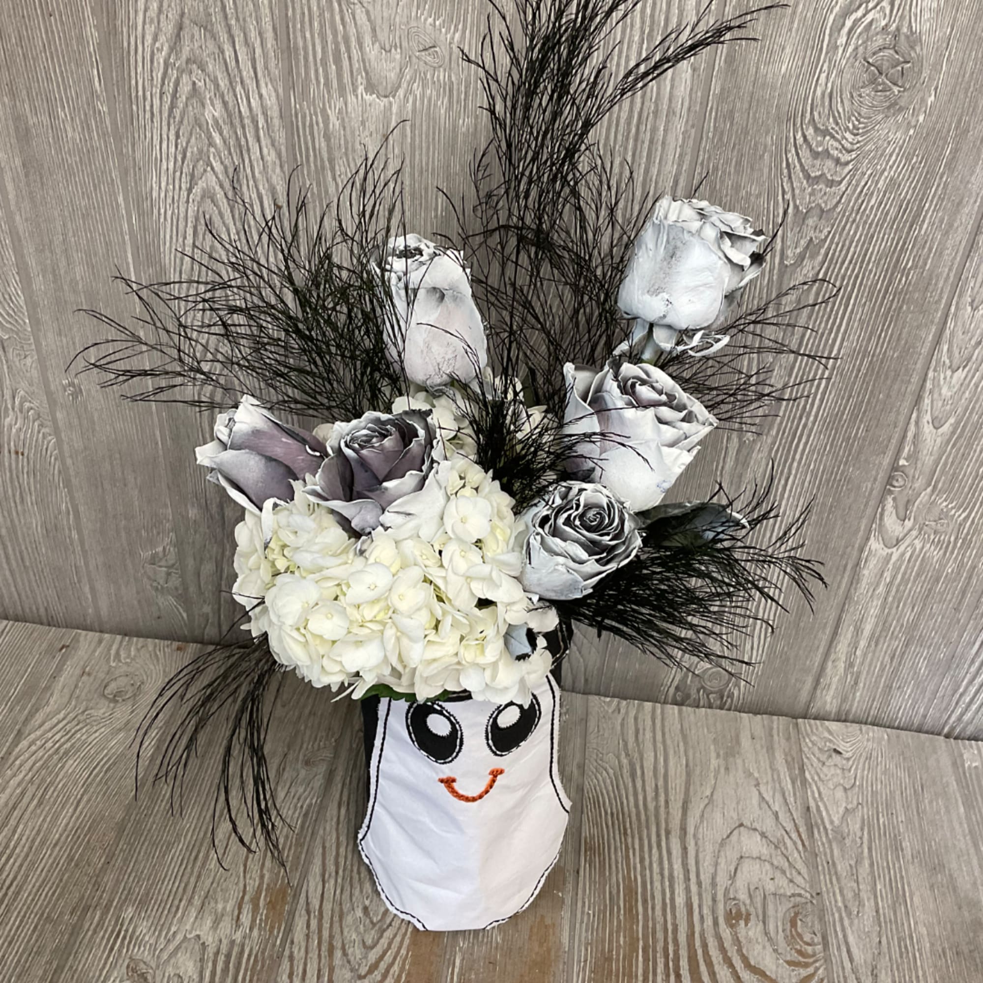 White and gray roses with white hydrangea in a ghost-shaped container