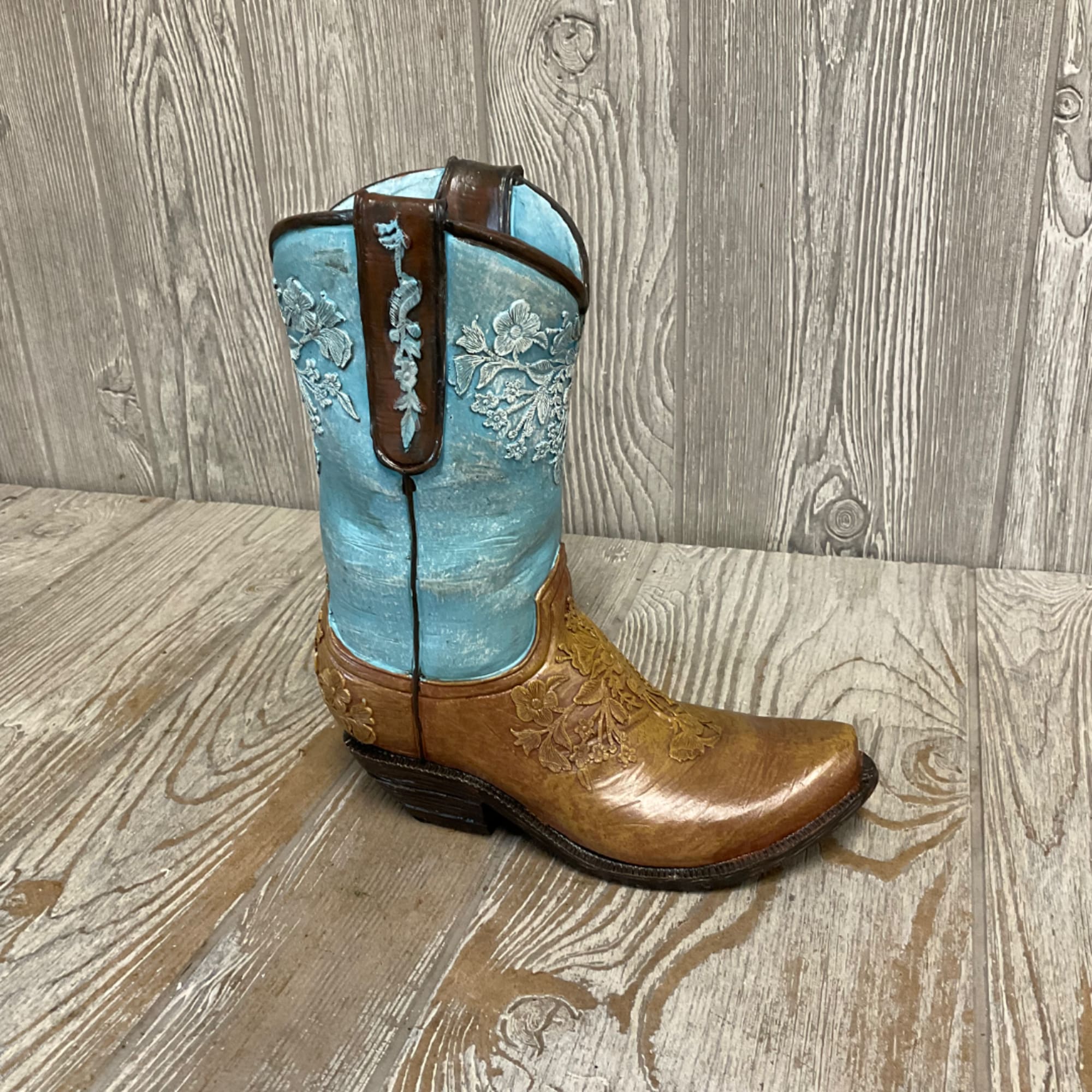 Decorative turquoise and brown cowboy boot on a wood floor