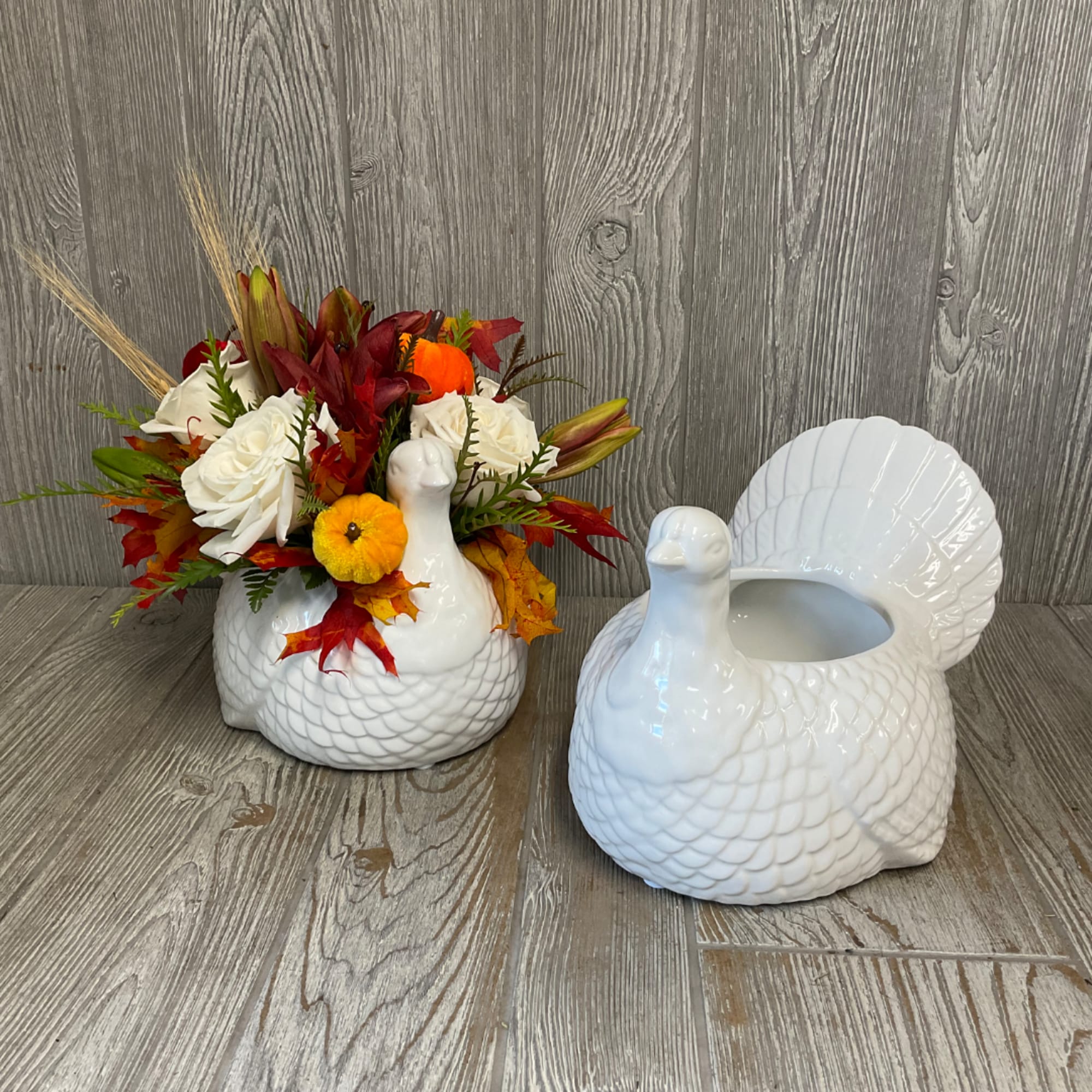 White floral arrangement in a ceramic turkey-shaped vase beside an empty matching vase