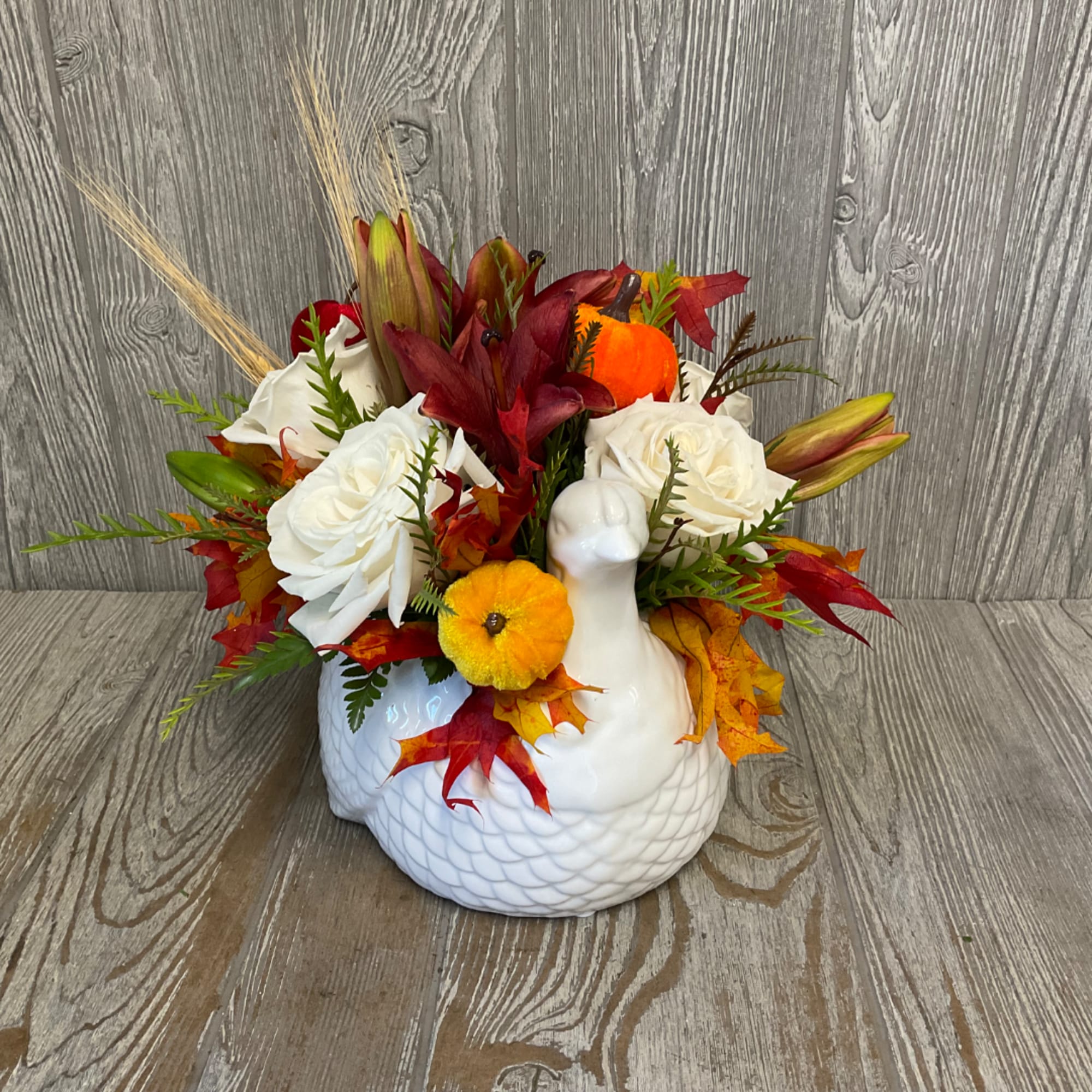 Autumn floral arrangement in a white ceramic turkey vase with white roses and red lilies