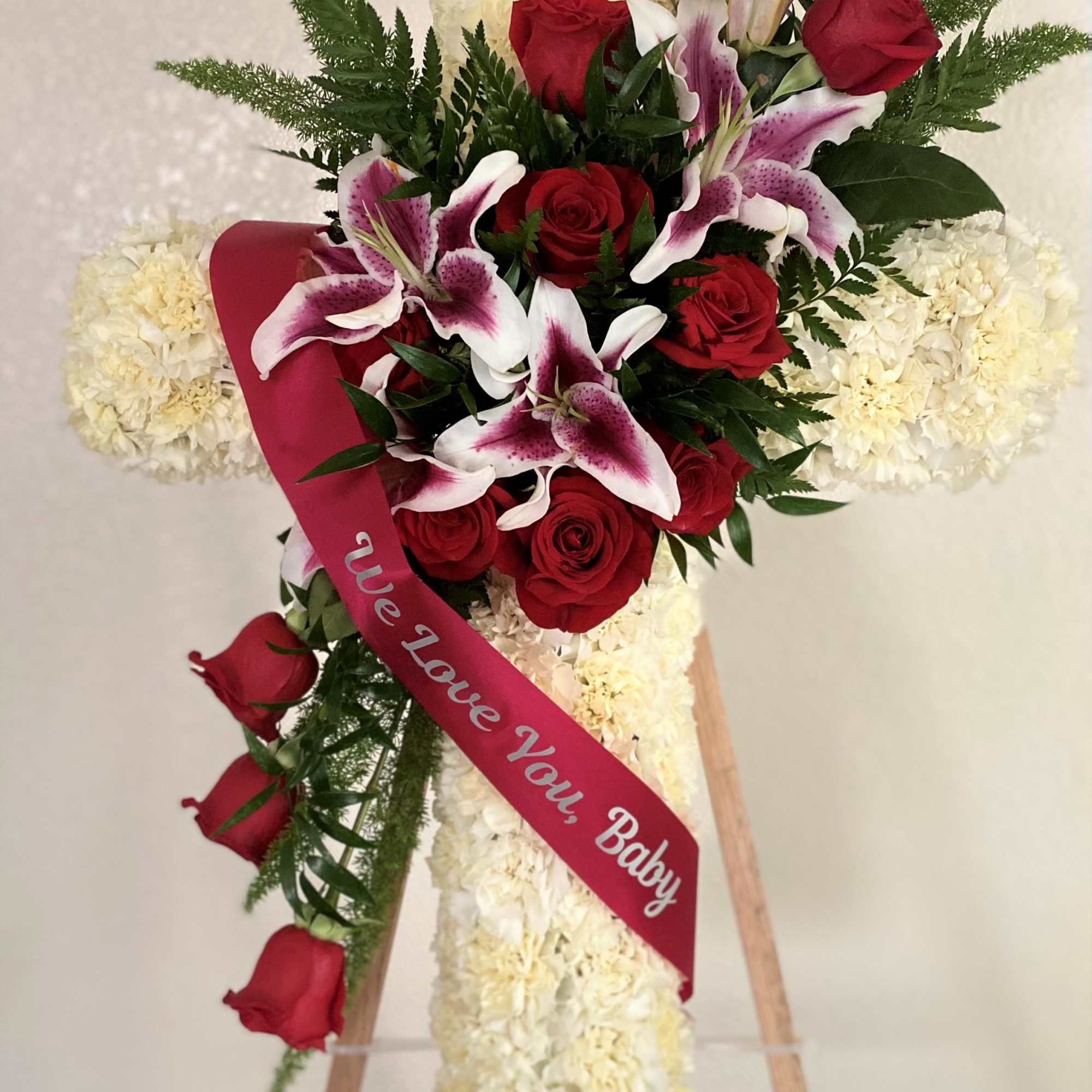 Standing floral cross with red roses and white lilies on an easel