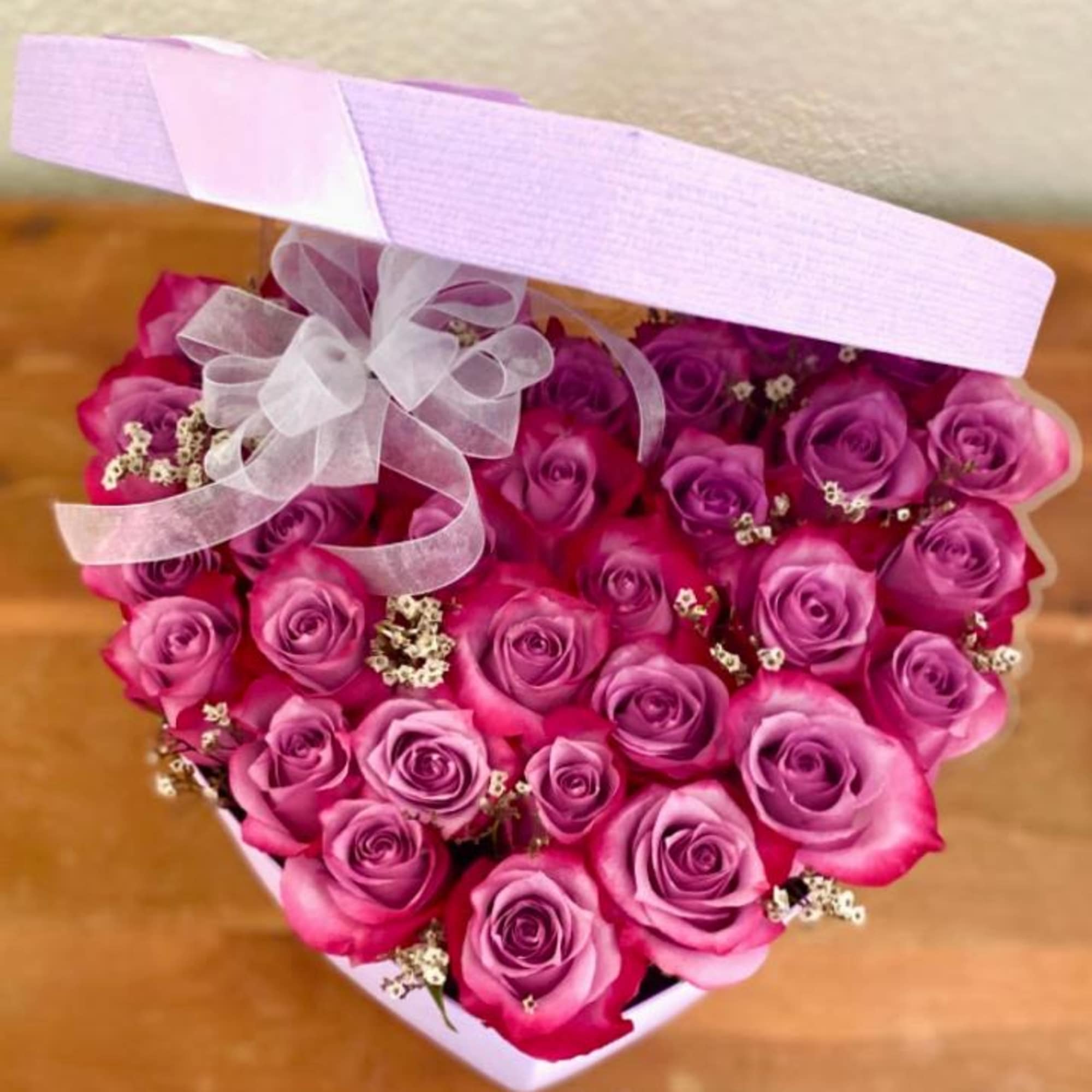Heart-shaped box of pink roses with a sheer ribbon bow