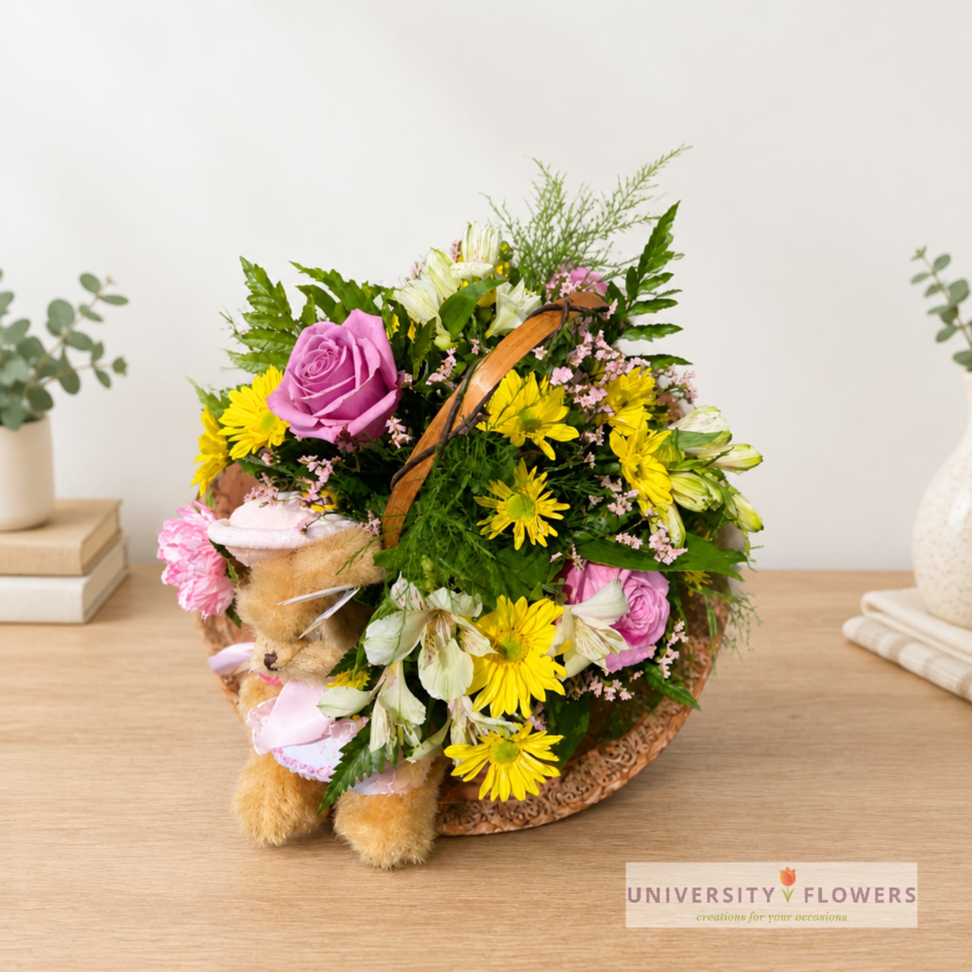 Flower basket with a teddy bear and mixed blooms in pink, yellow, and white