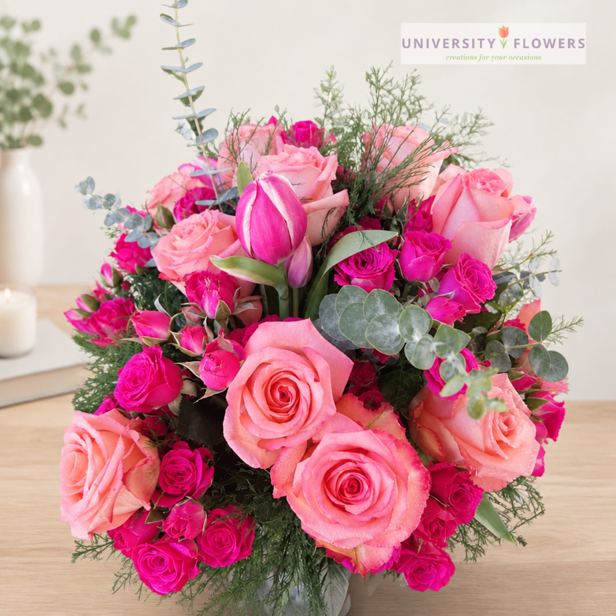 Pink roses and magenta spray roses in a vase with tulips and eucalyptus