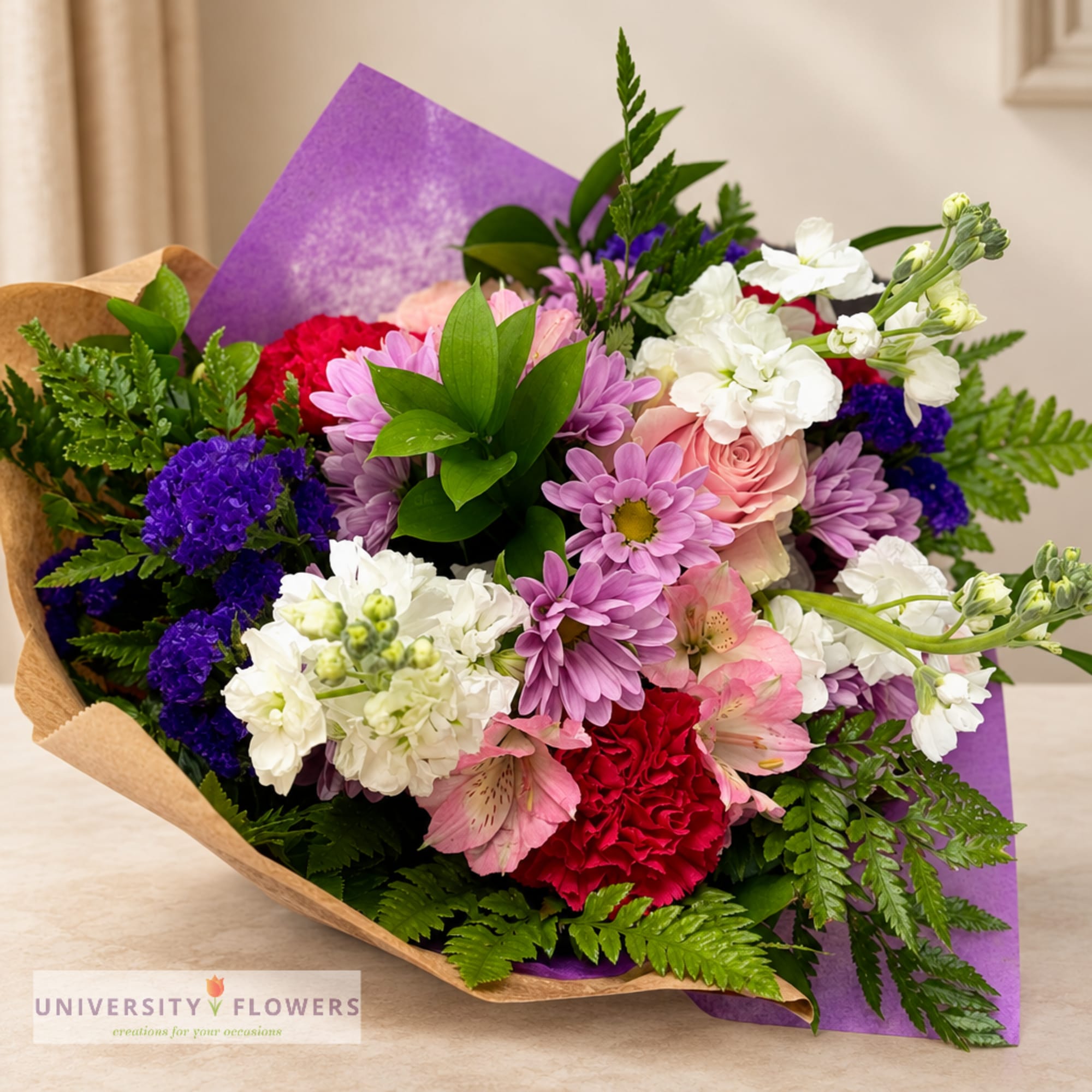 Mixed bouquet of pink, white, purple, and red flowers wrapped in brown paper