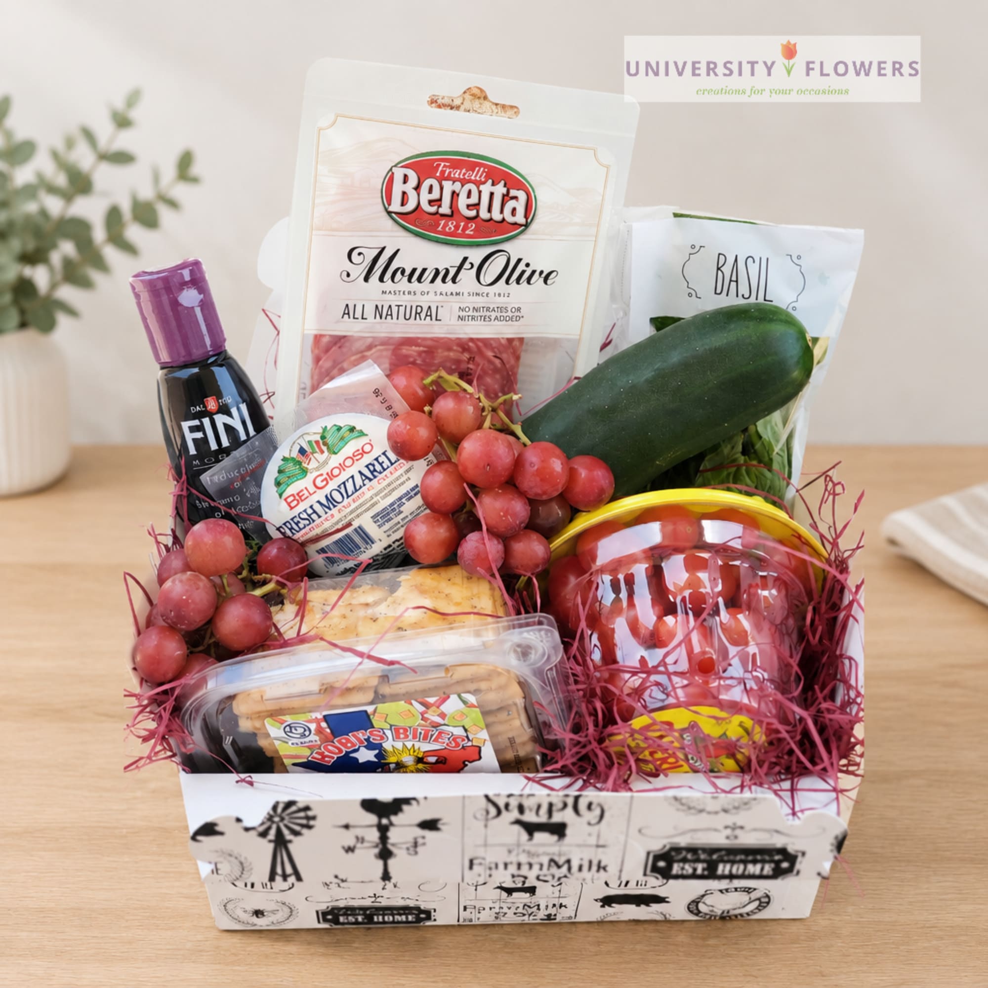 Gift basket with packaged snacks, grapes, zucchini, and basil in a decorative box