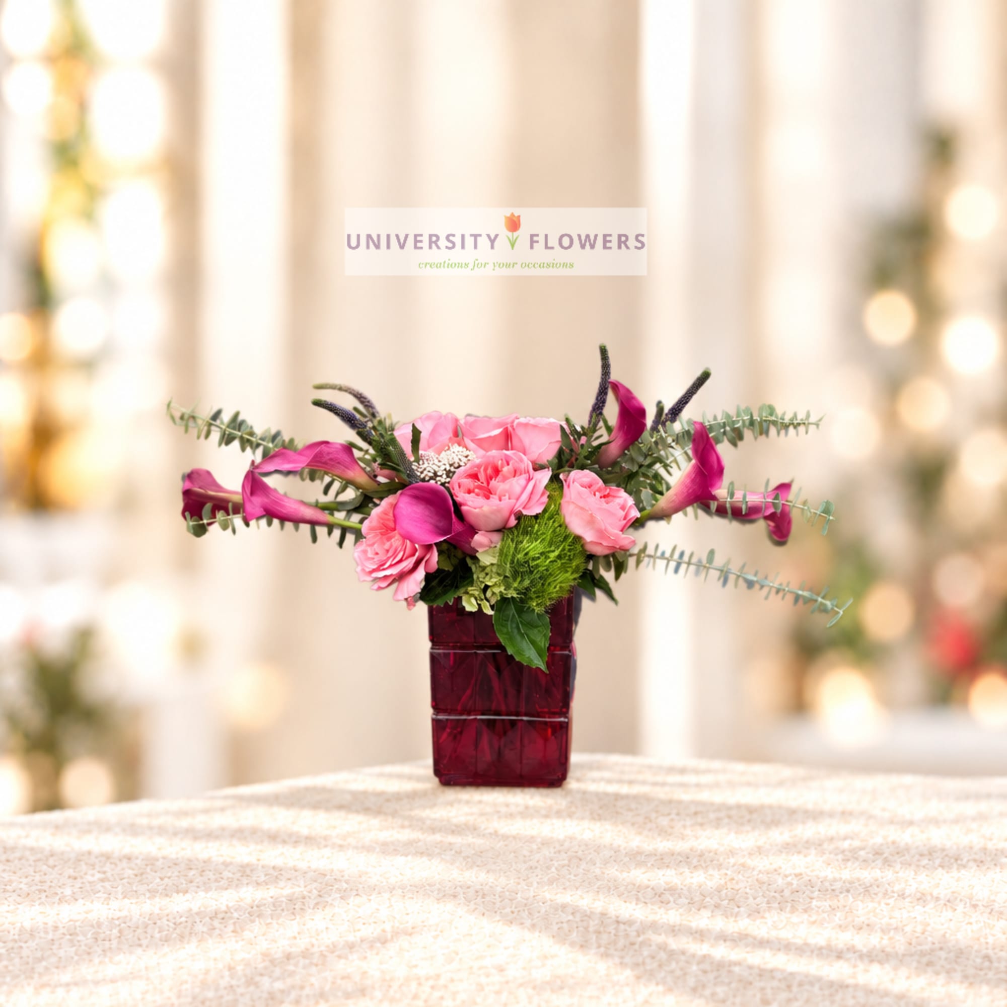 Pink floral arrangement in a burgundy vase with long purple accents