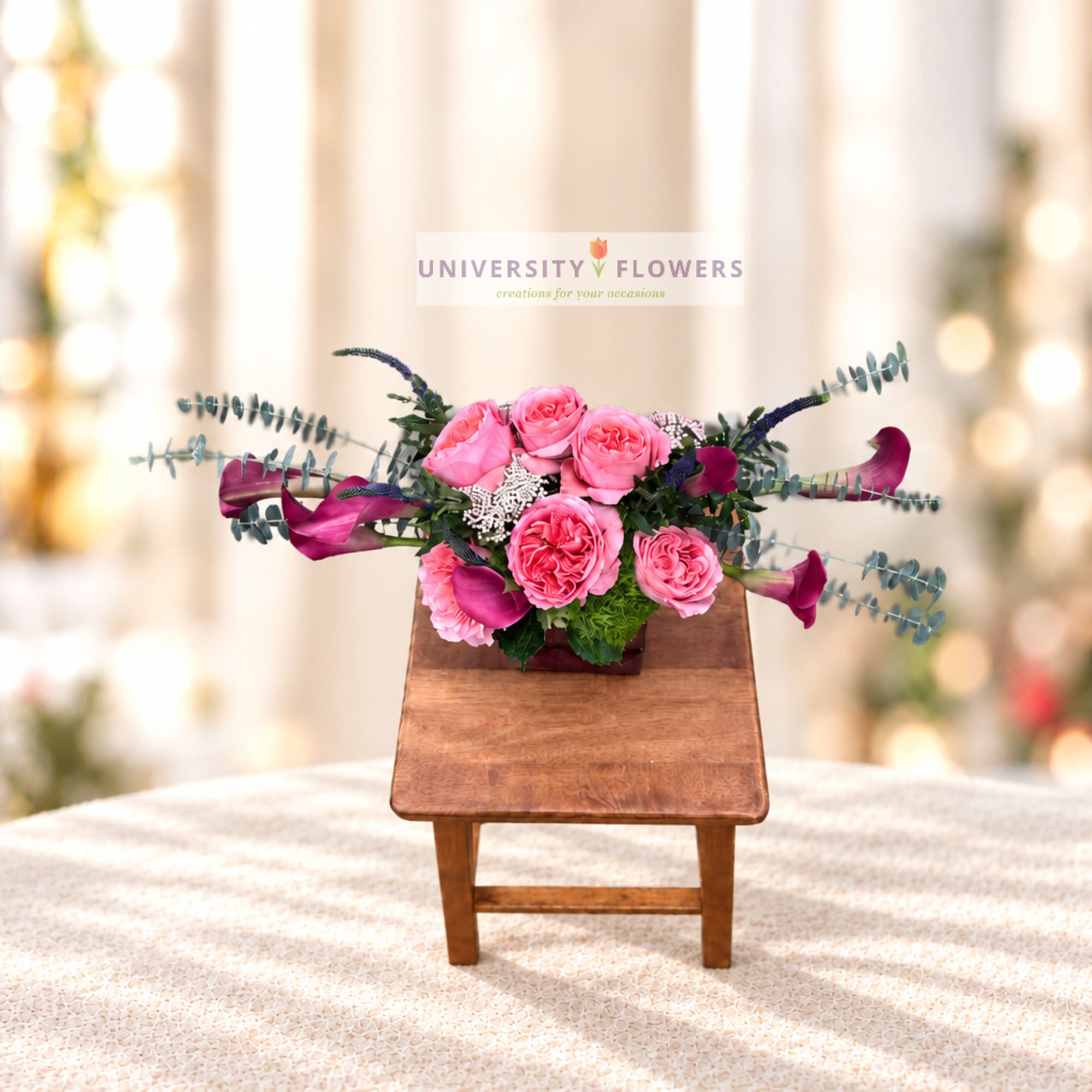 Pink rose arrangement with purple calla lilies in a wooden container