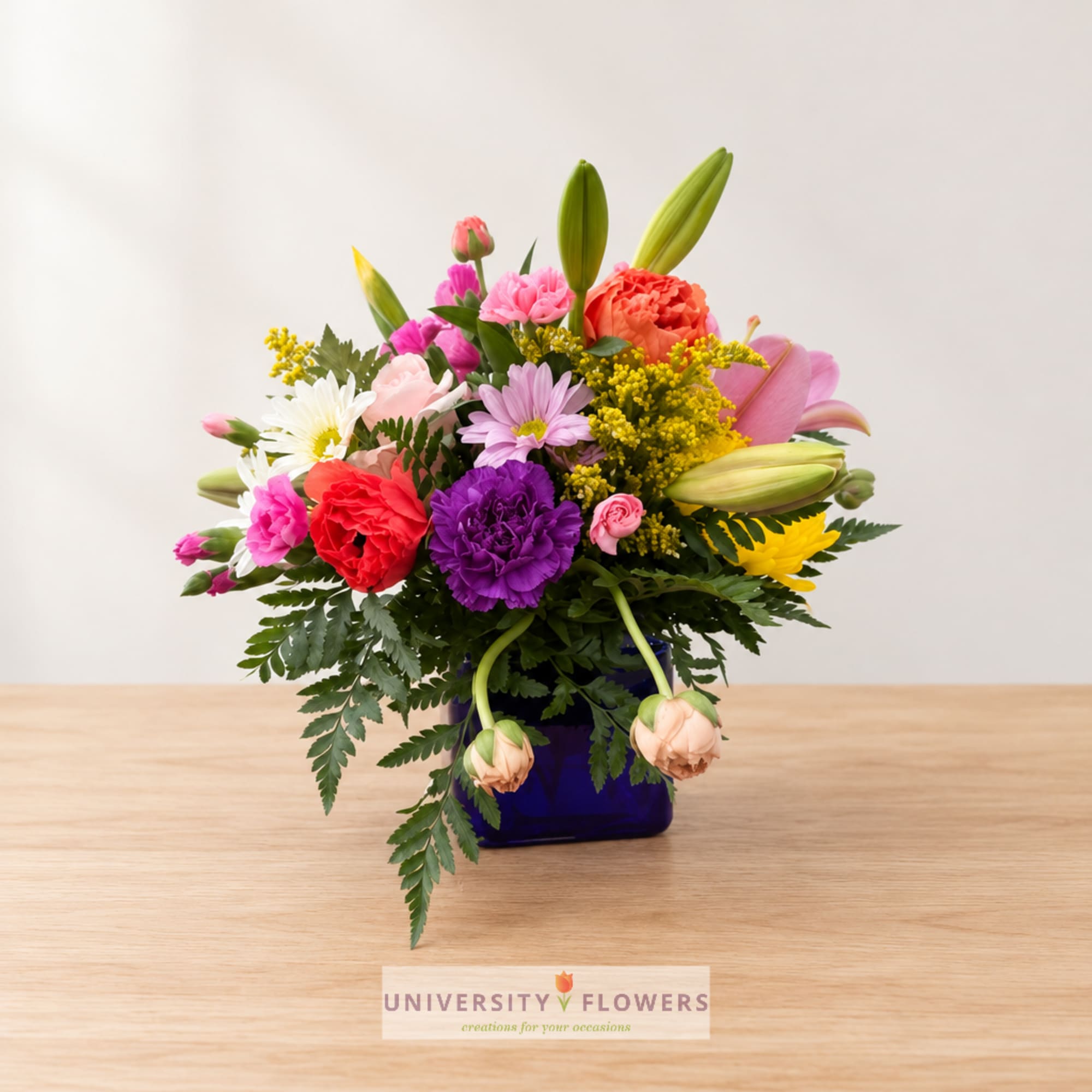 Colorful mixed bouquet in a blue vase on a wooden table