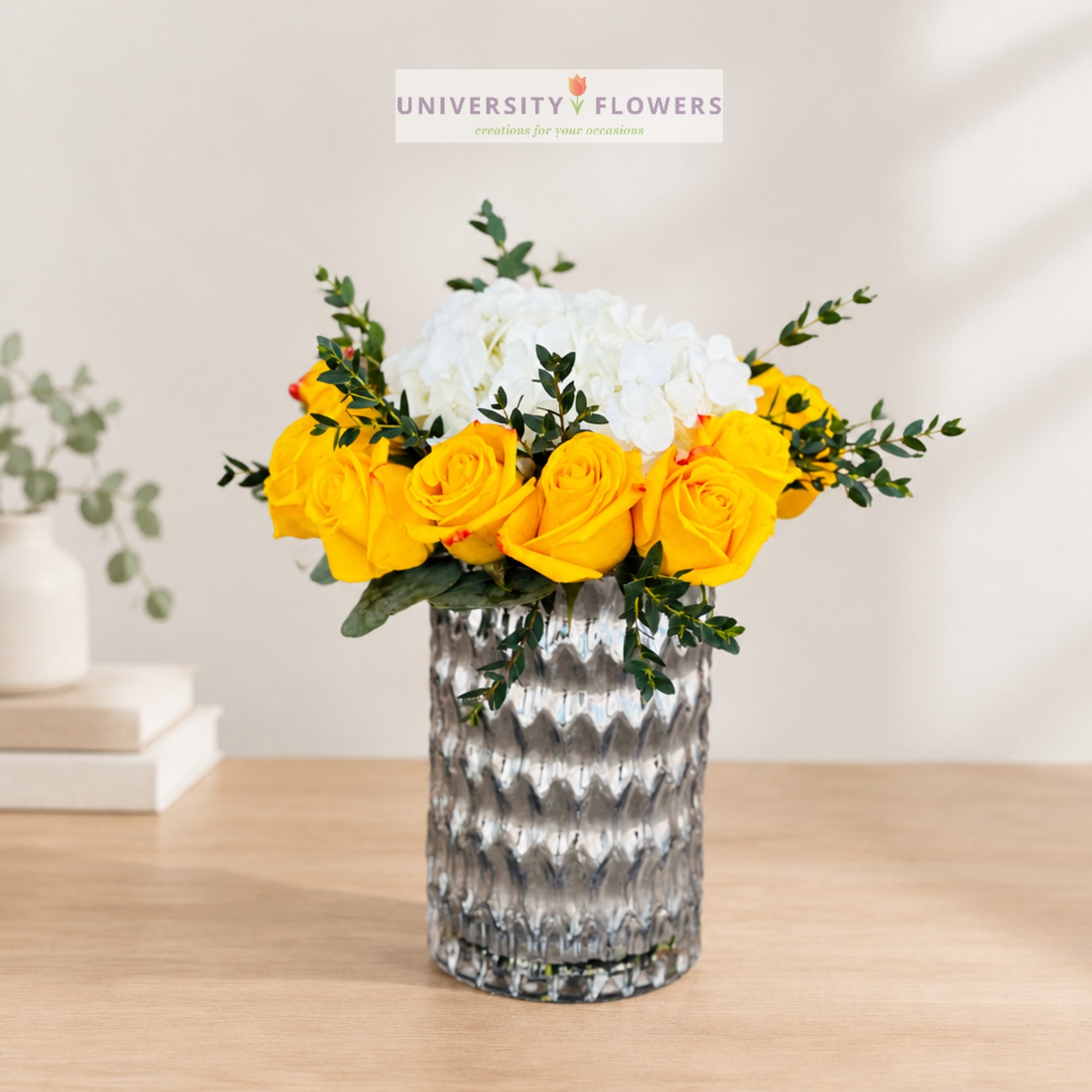 Yellow and white rose arrangement in a textured glass vase