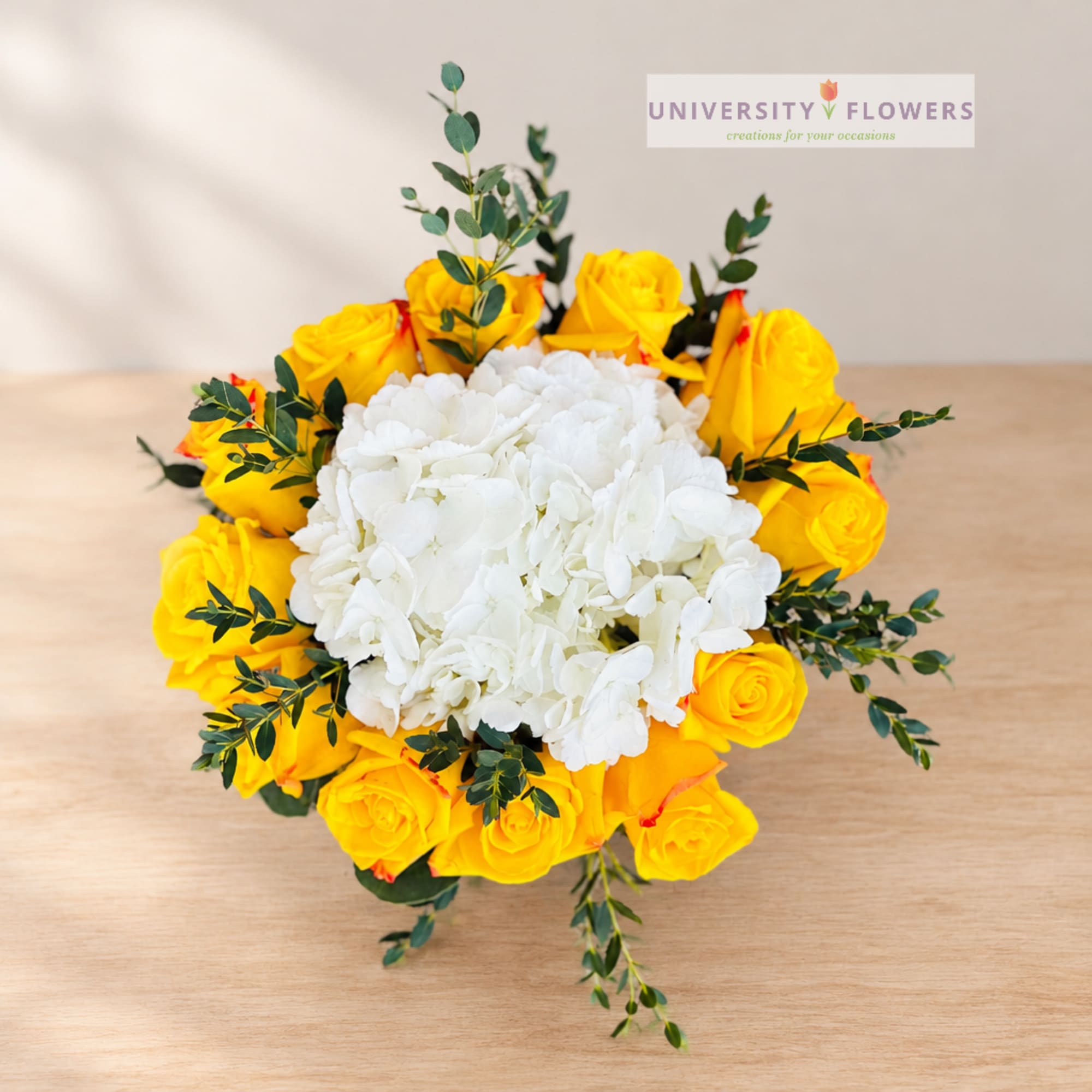 Yellow roses surrounding a white hydrangea bouquet on a table