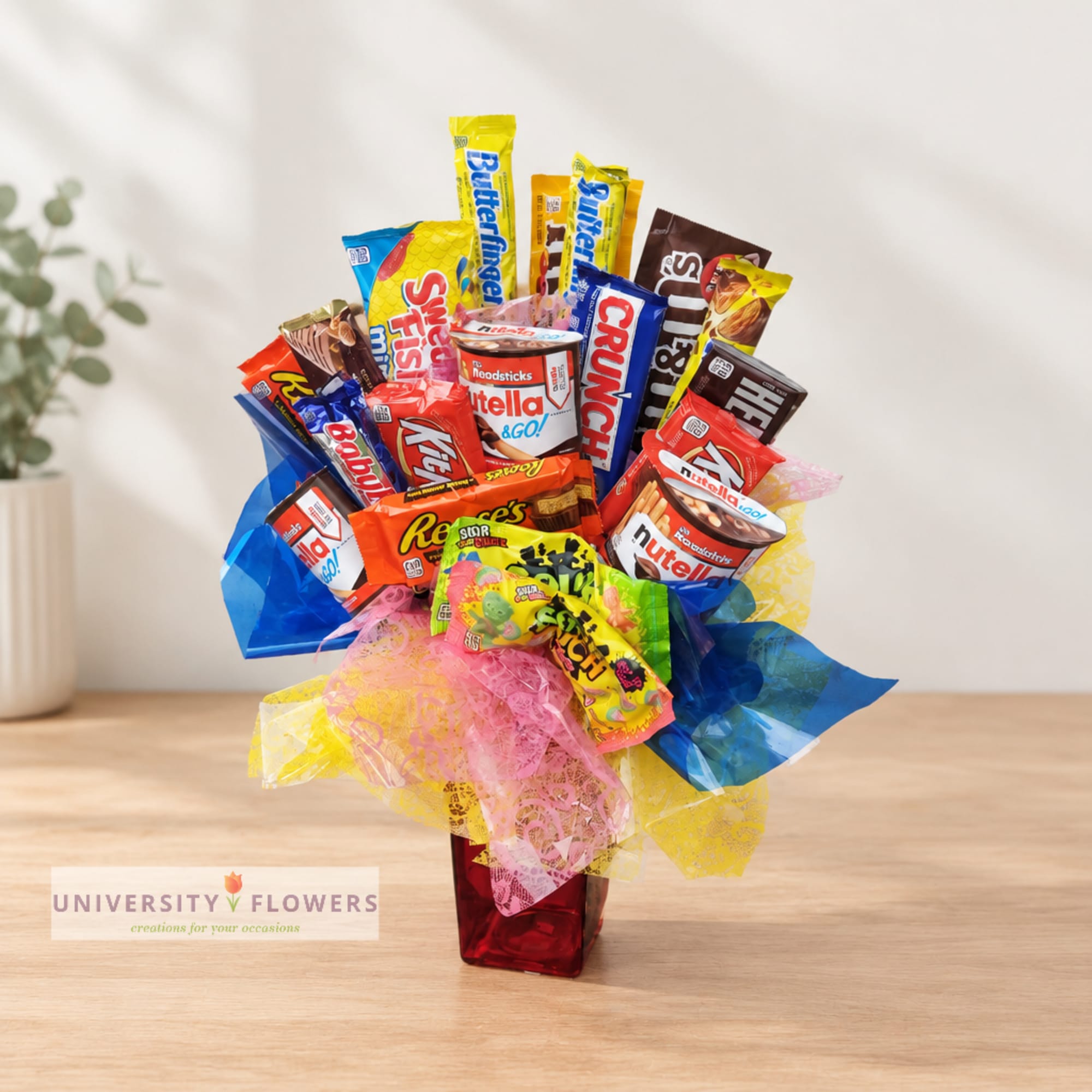 Candy bouquet in a red vase with colorful snack bars and wrappers