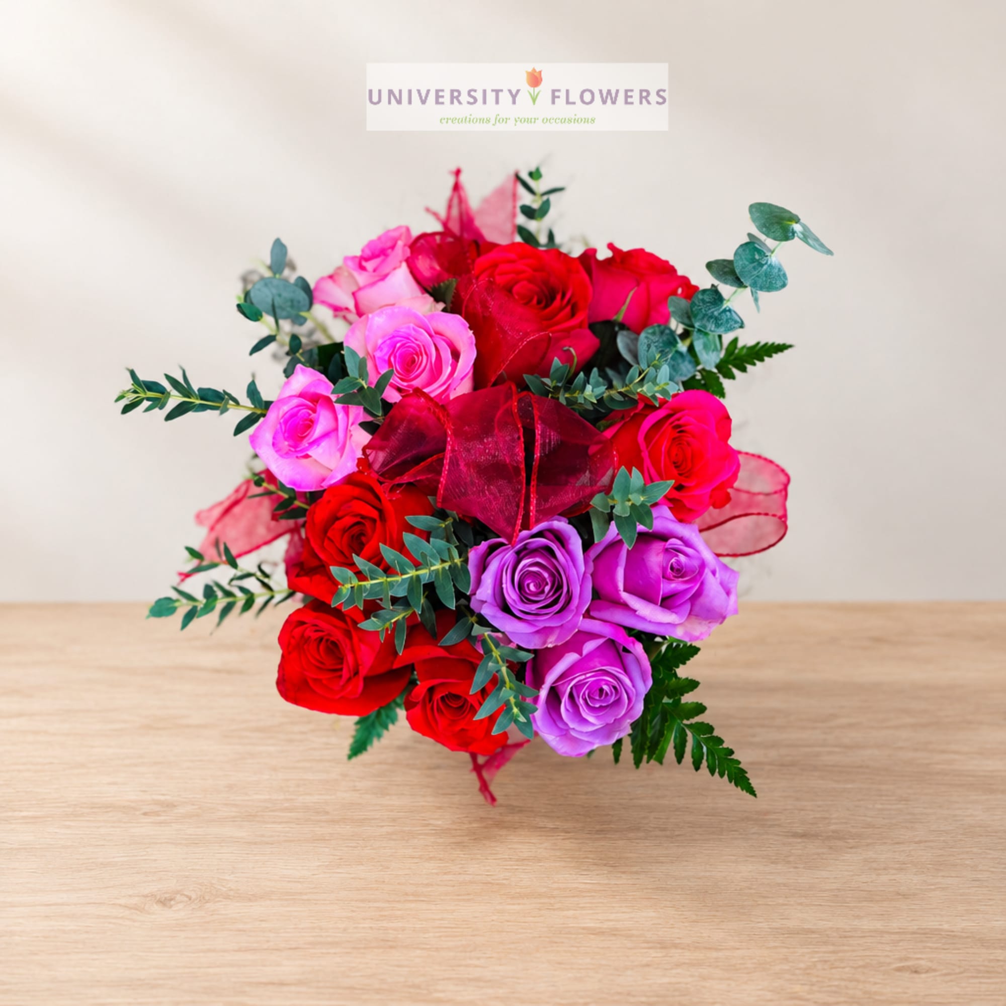 Bouquet of red, pink, and purple roses with ribbon accents