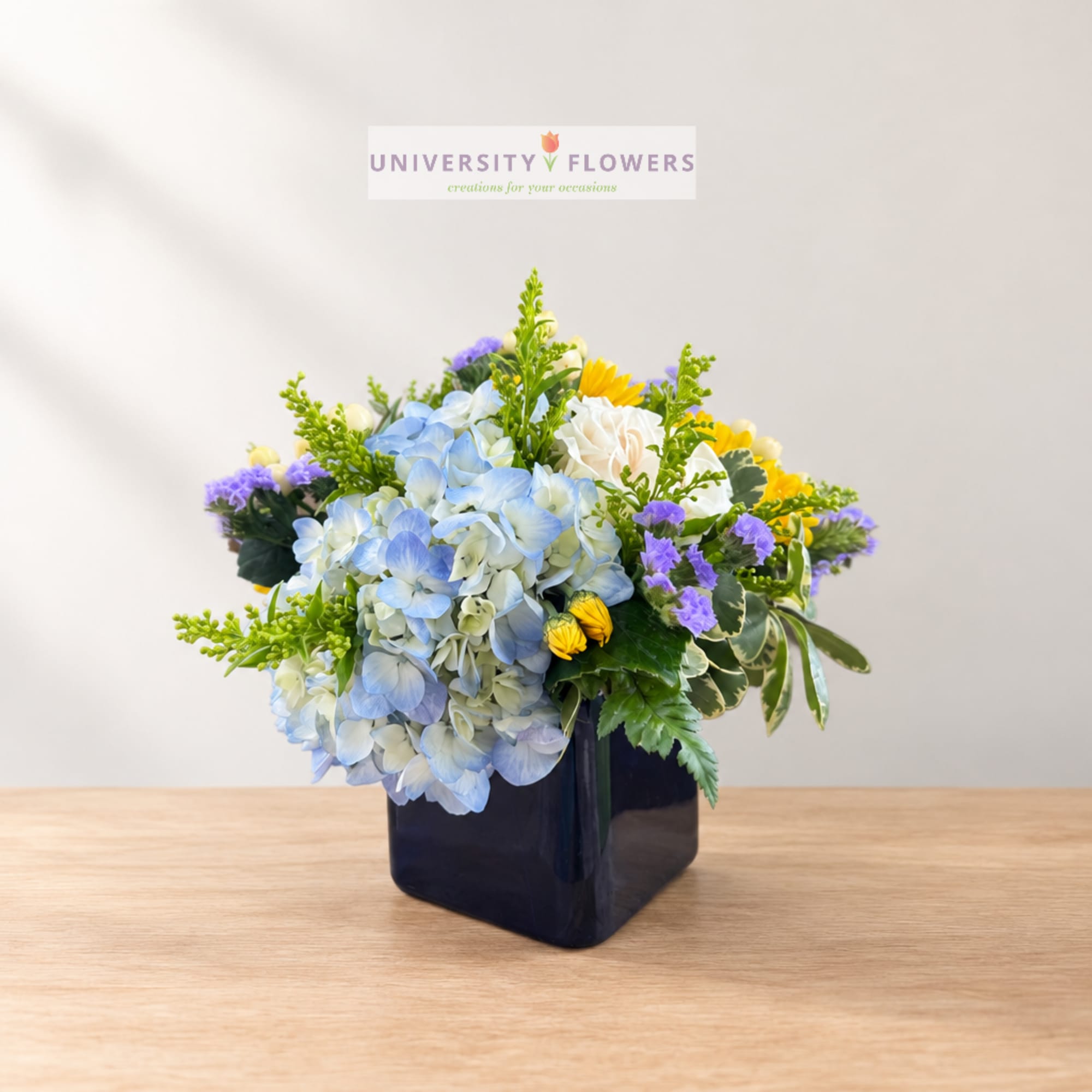 Blue and white floral arrangement in a dark square vase