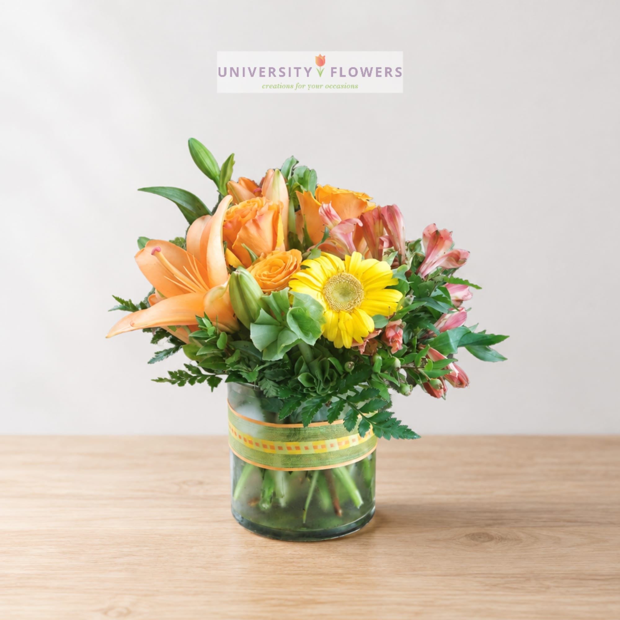 Orange lilies and yellow gerbera daisies in a glass vase