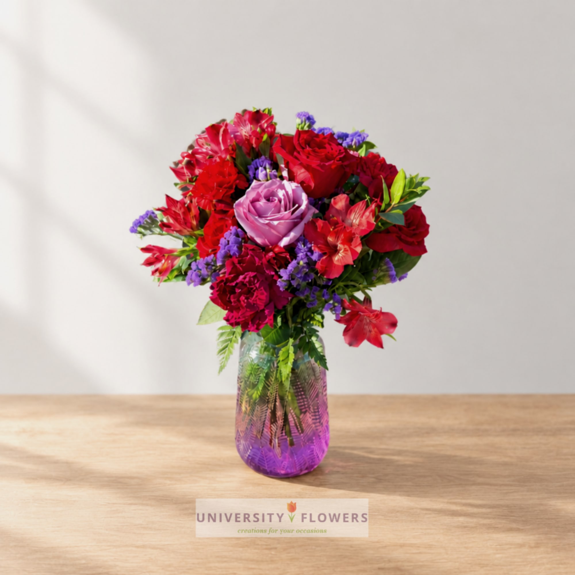 Mixed bouquet of red, pink, and purple flowers in a glass vase