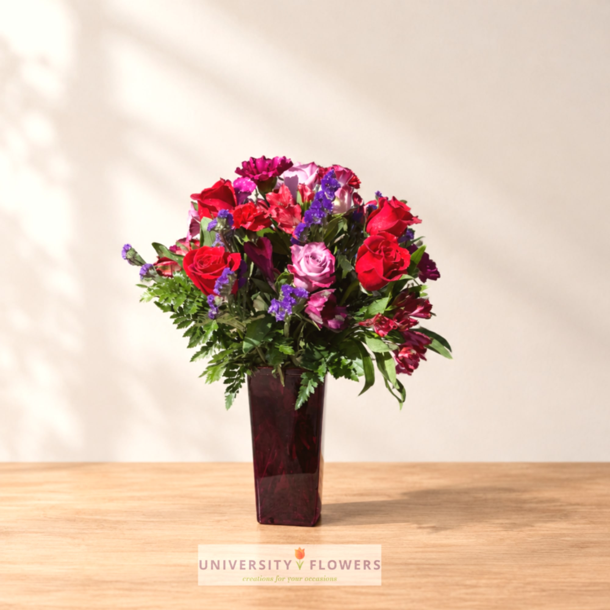 Mixed bouquet of red and pink roses in a tall purple vase