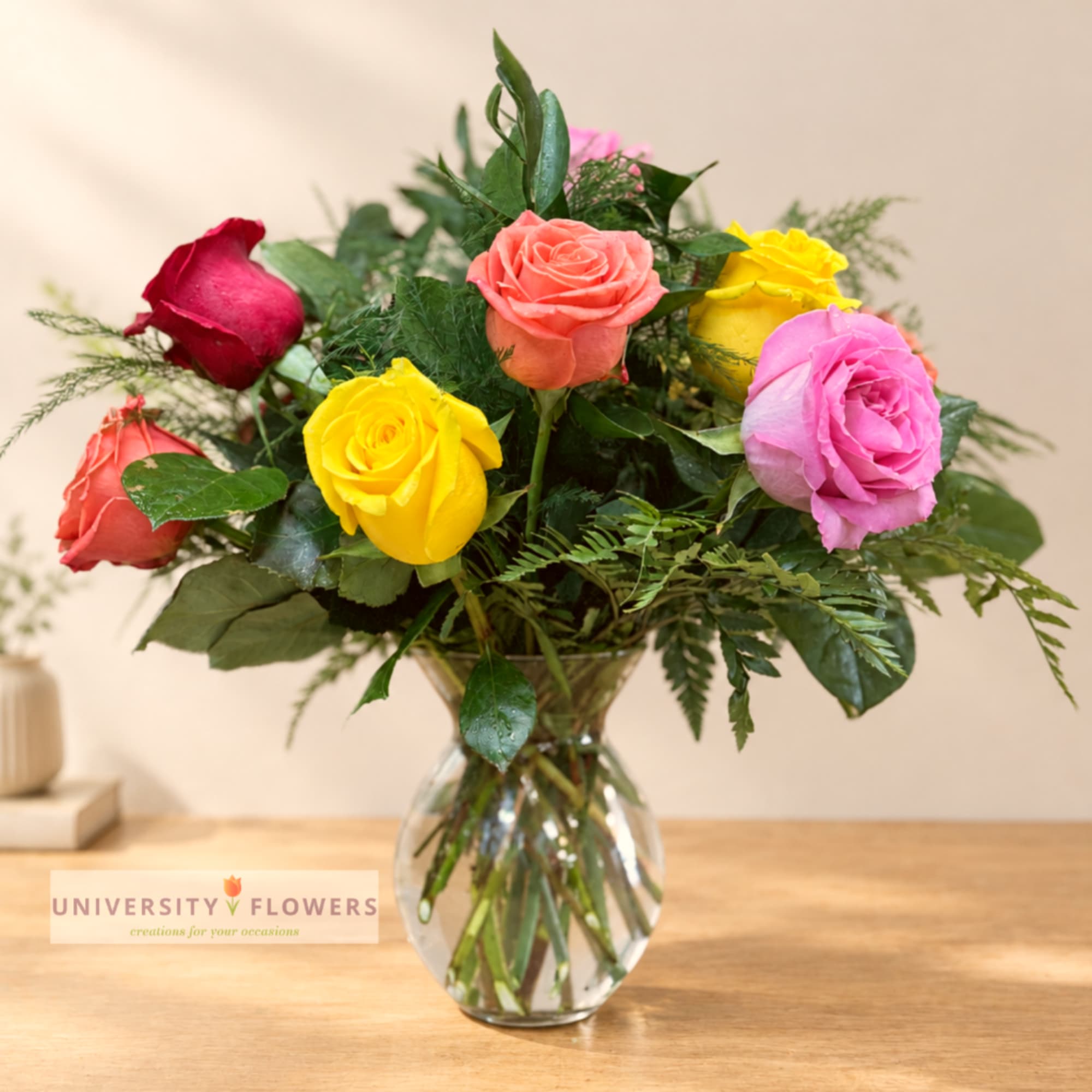 Mixed roses in a clear glass vase on a wooden table