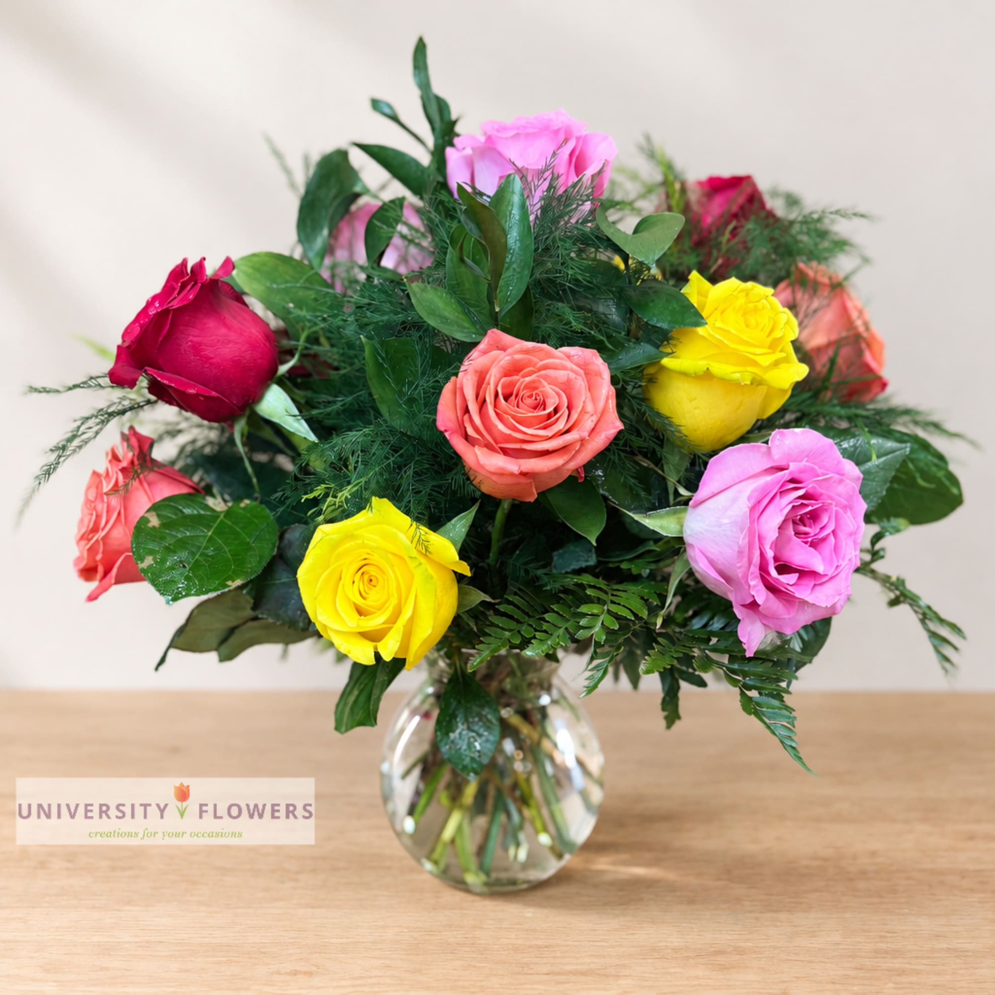 Mixed roses in a clear glass vase with dense greenery