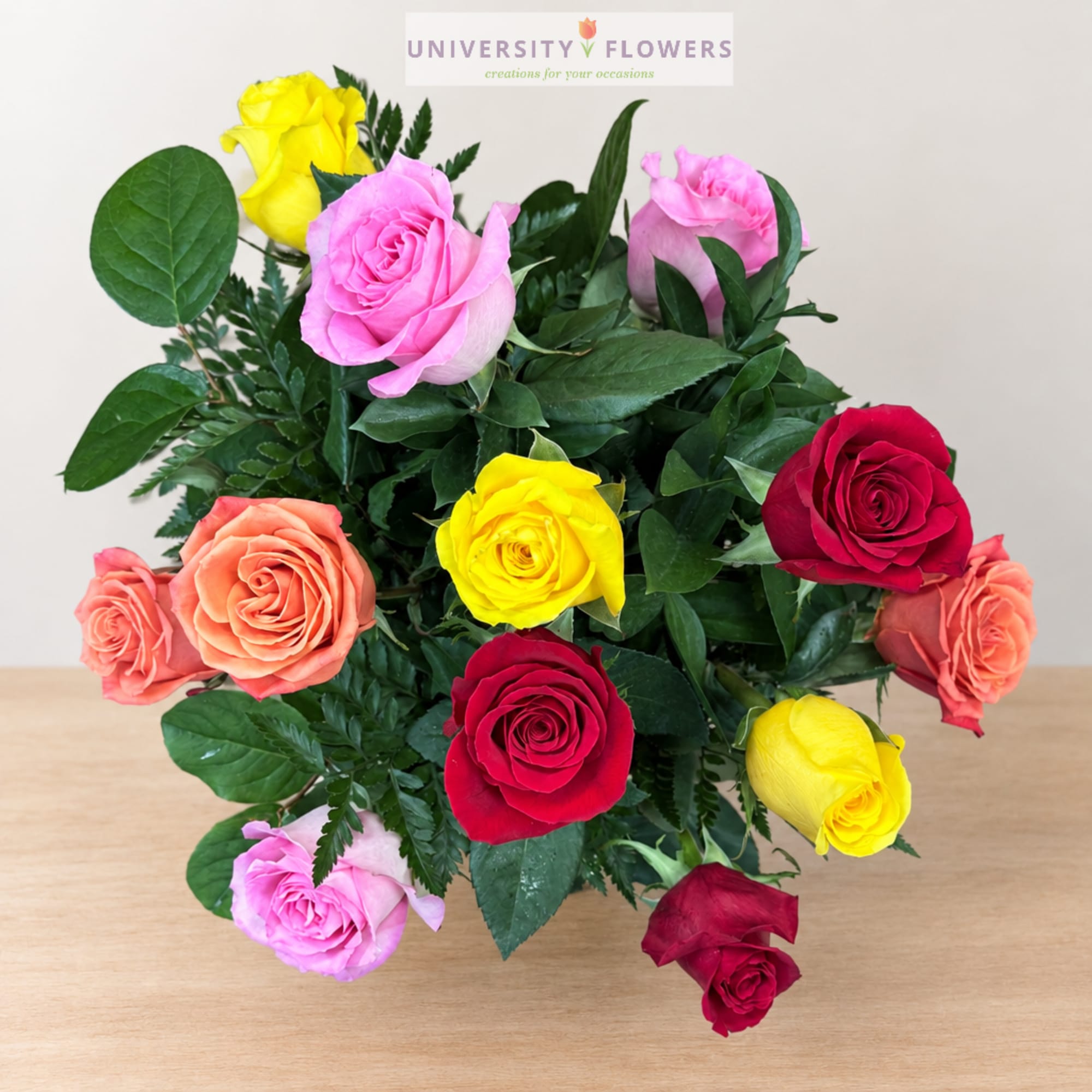 Mixed bouquet of colorful roses with greenery on a table
