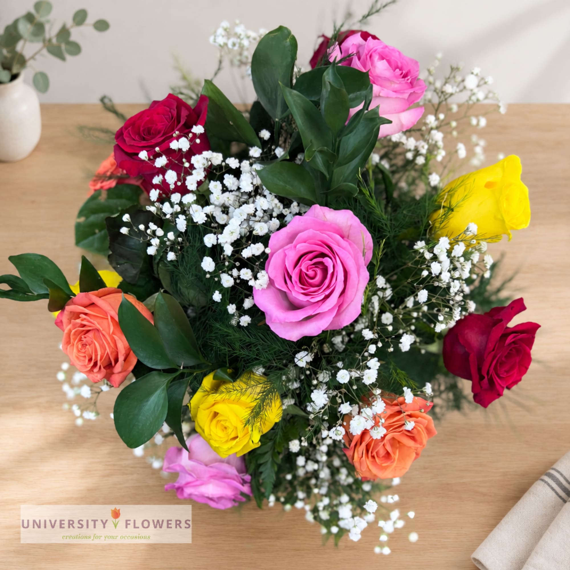 Mixed roses with baby's breath in a low bouquet on a wooden table
