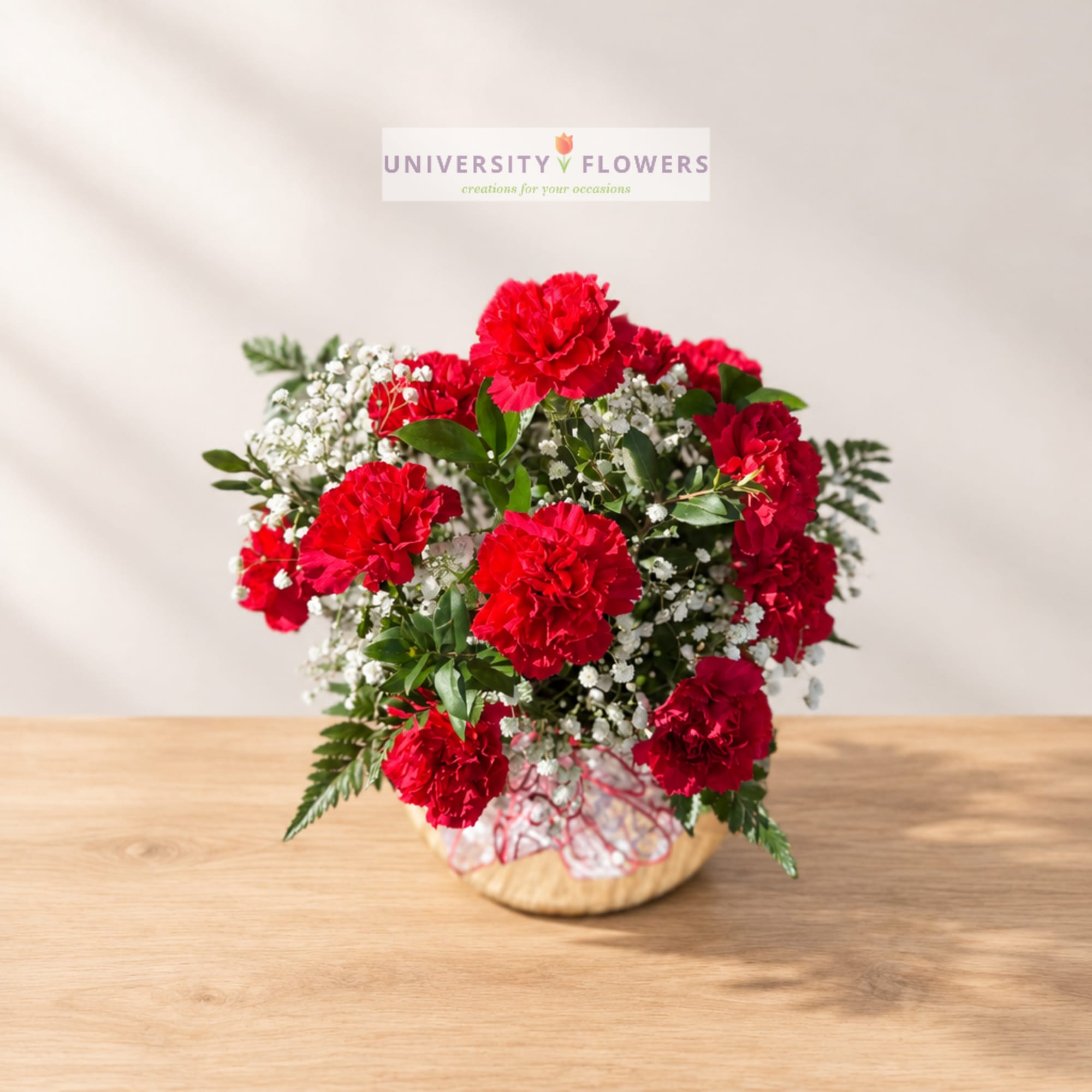 Red carnations in a round basket with baby's breath