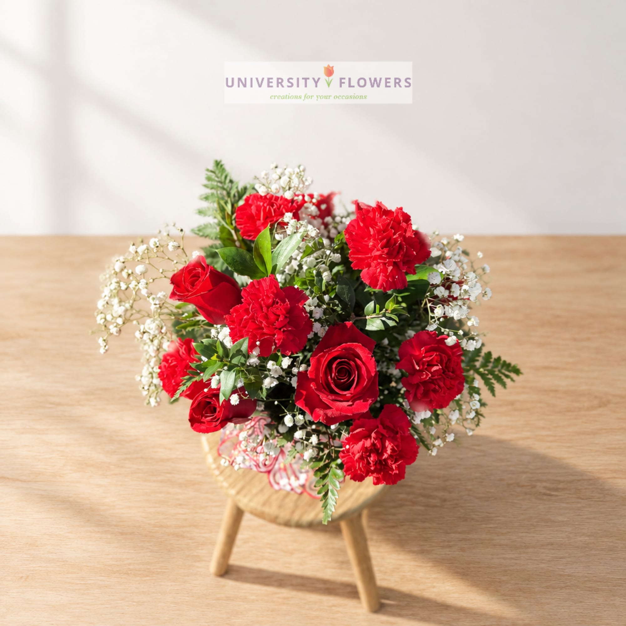 Red roses and carnations in a small round wooden stand