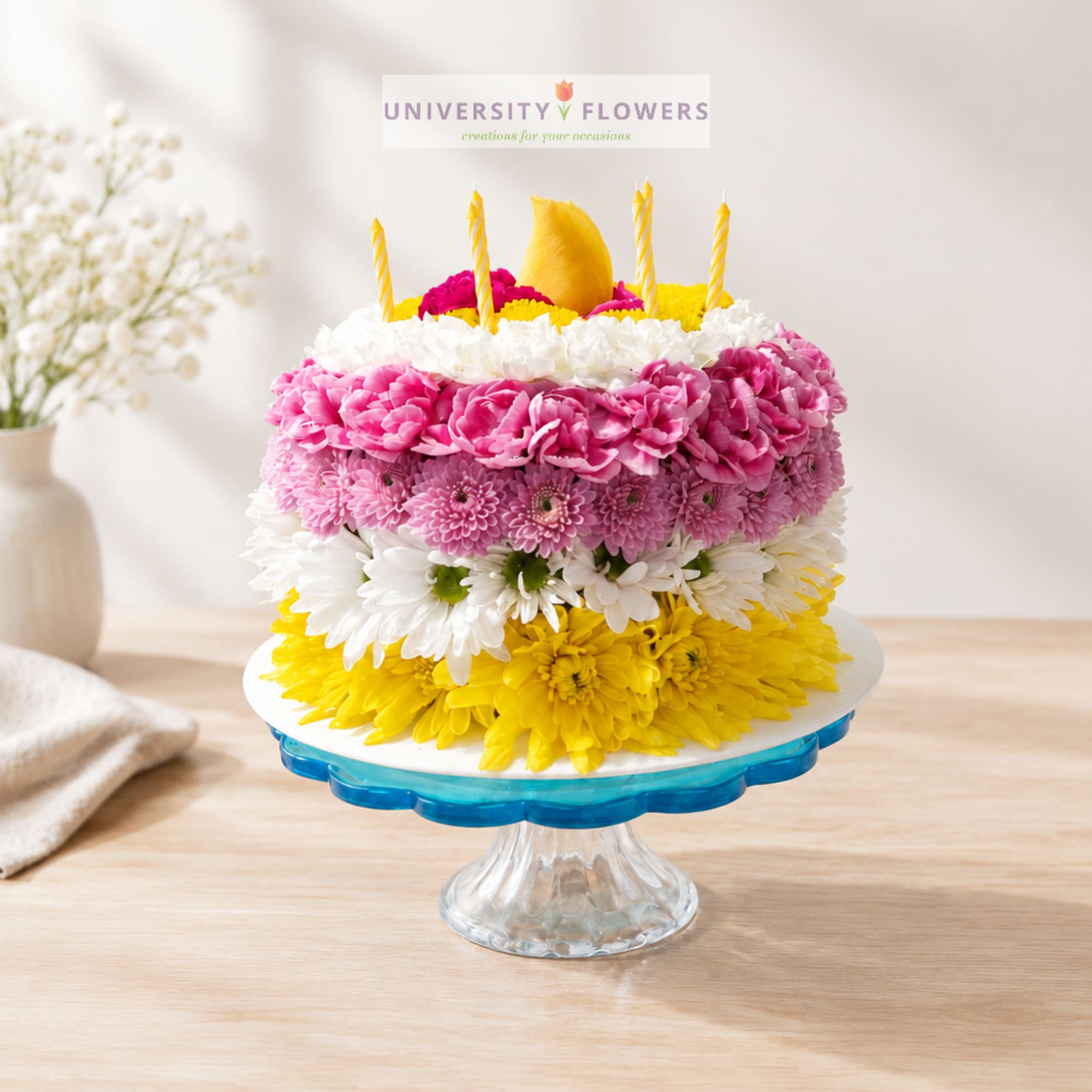 Colorful flower cake with candles on a glass pedestal stand