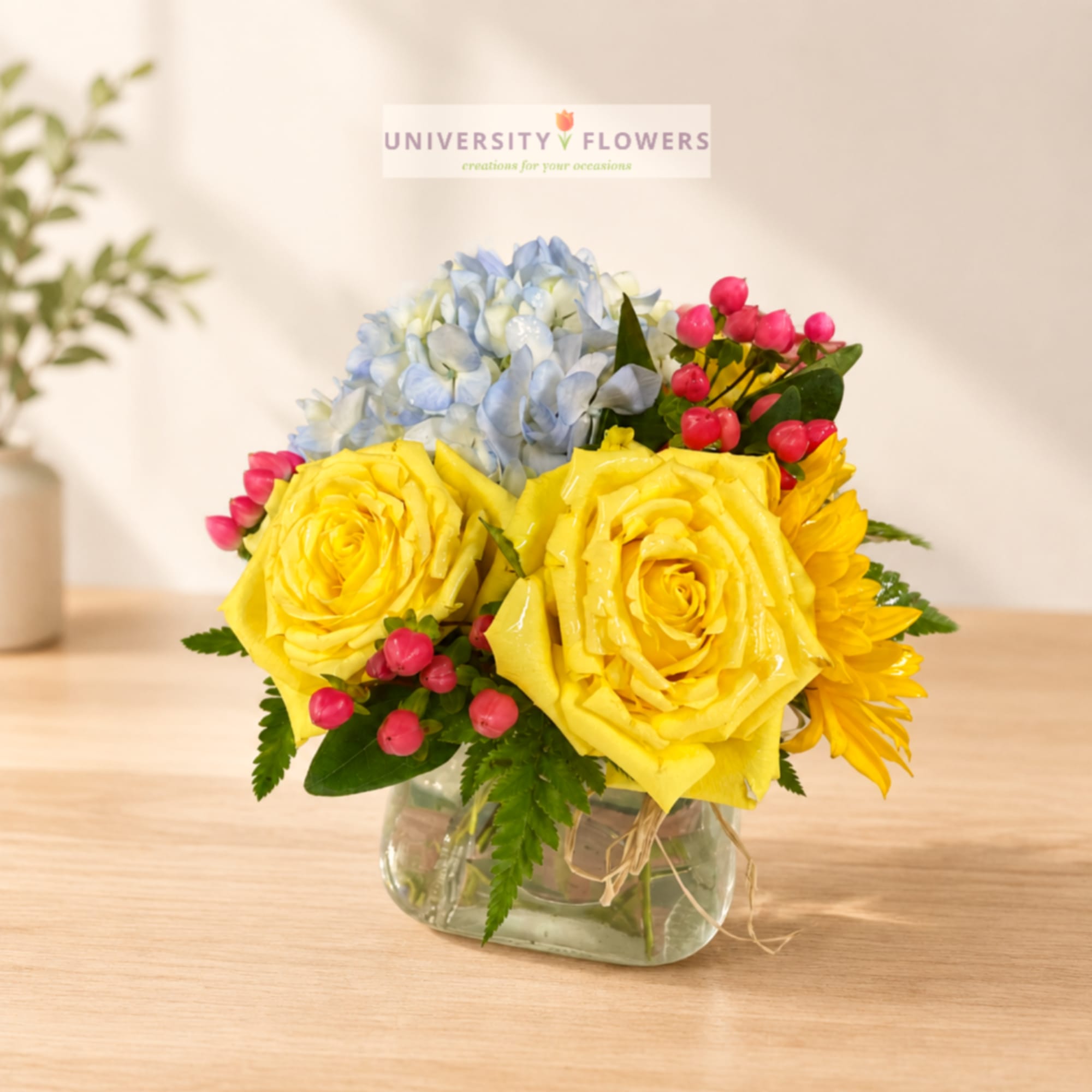 Yellow roses and blue hydrangeas in a clear glass vase