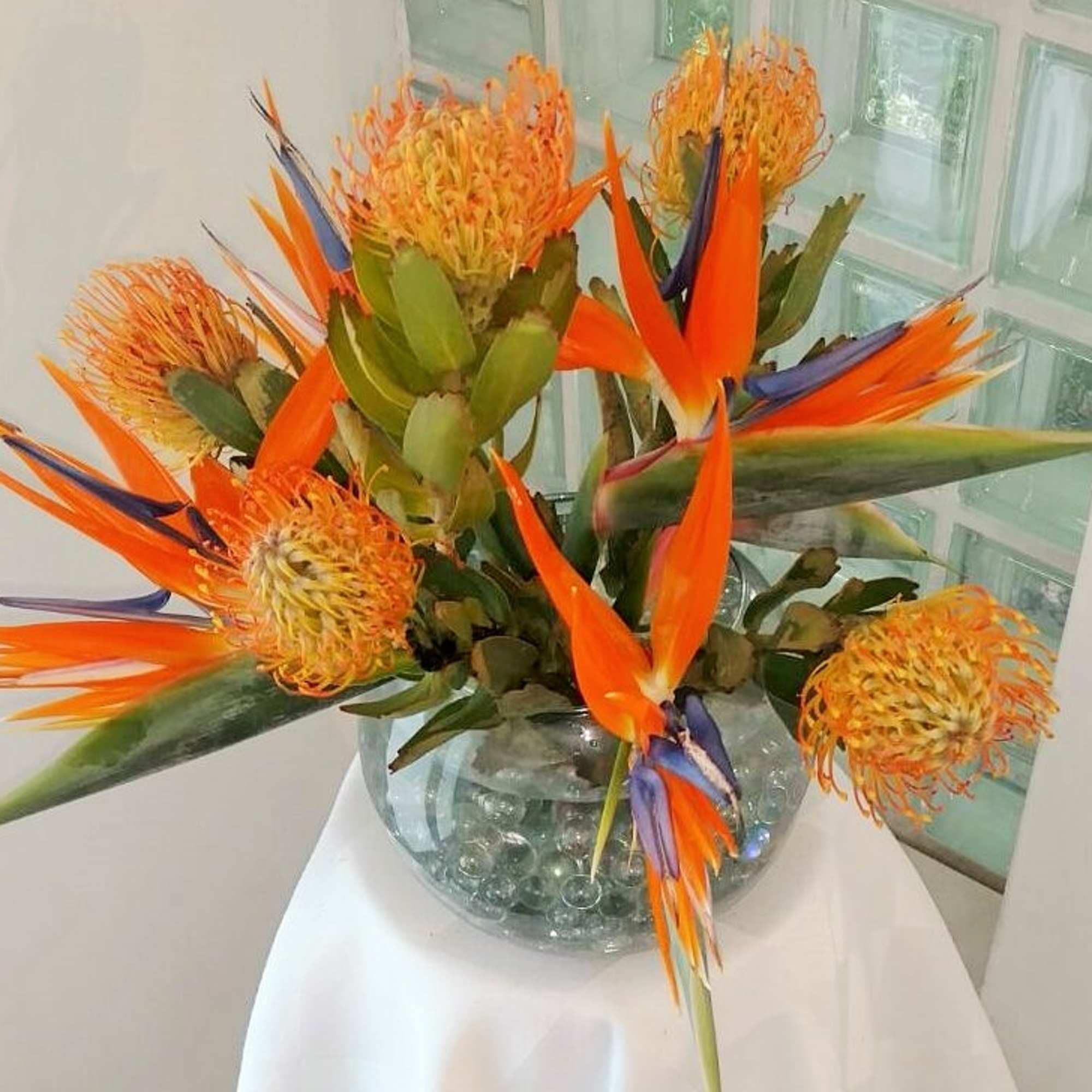 Orange and blue bird-of-paradise flowers in a glass vase