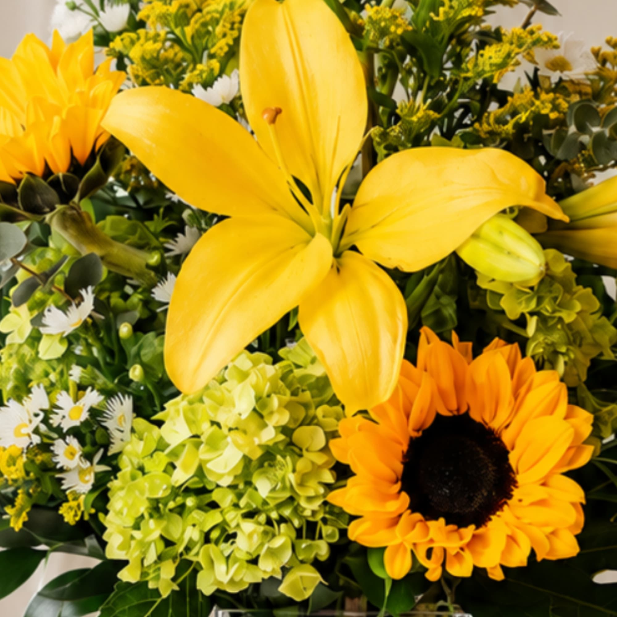 Yellow lilies and sunflowers in a mixed bouquet with green hydrangeas
