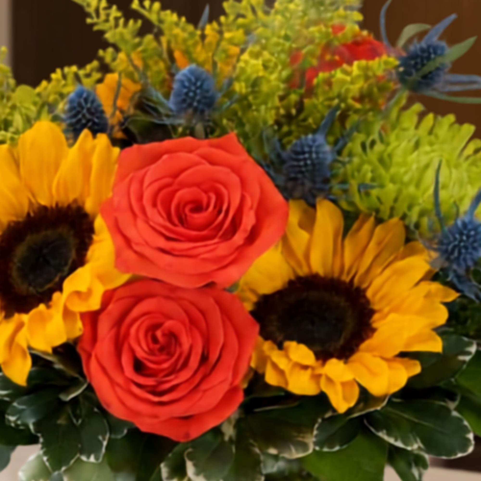 Bouquet of red roses and yellow sunflowers with blue thistle accents