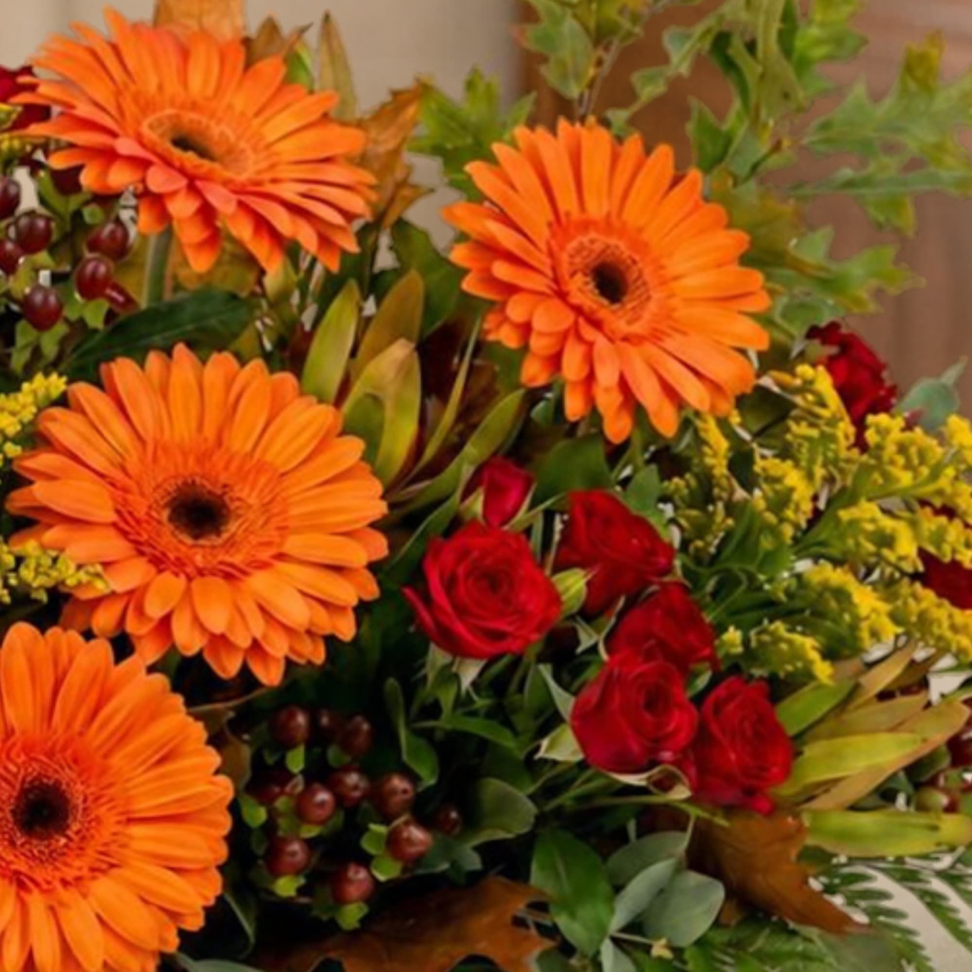 Bouquet of orange gerbera daisies and red roses with mixed greenery