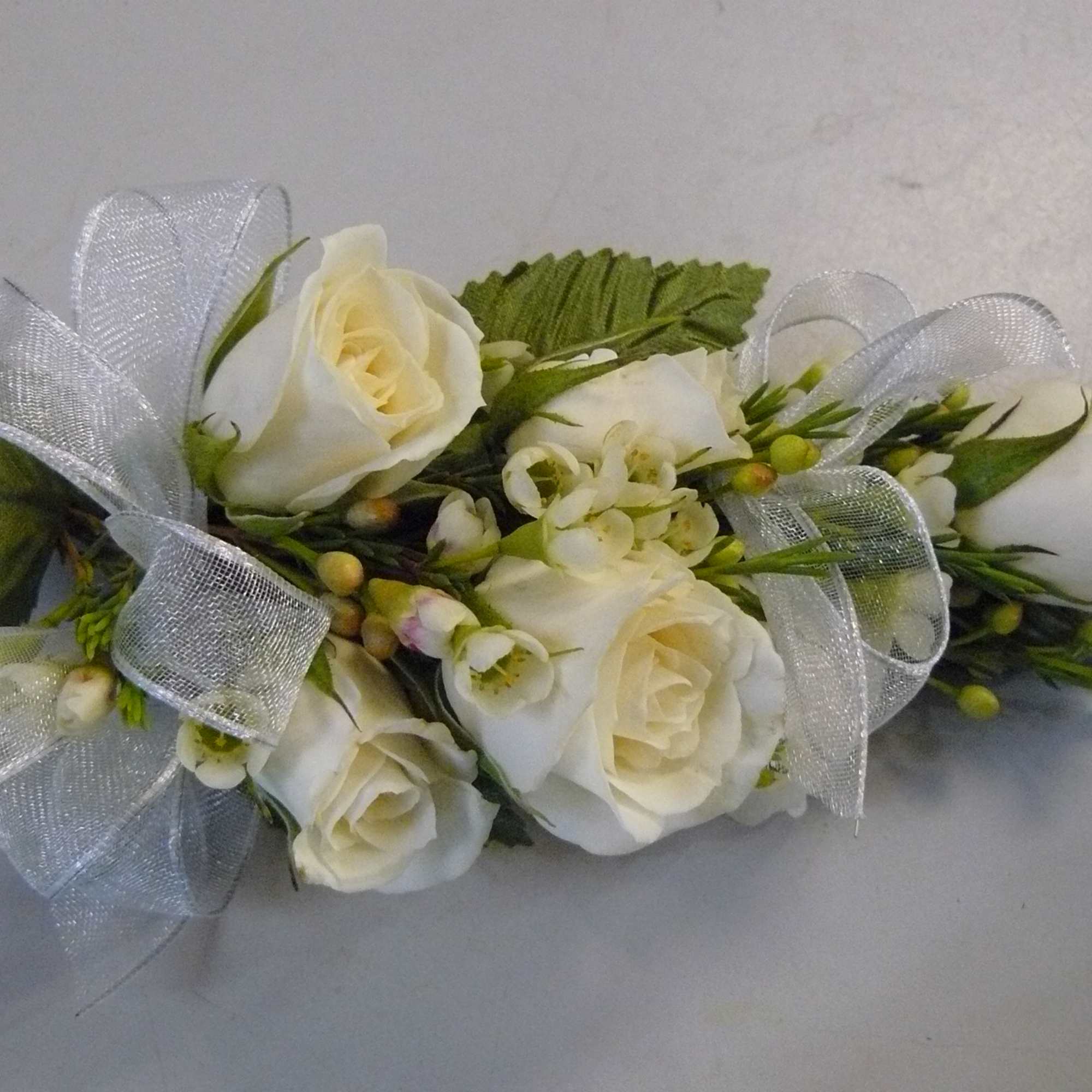 White rose corsage with ribbon and greenery