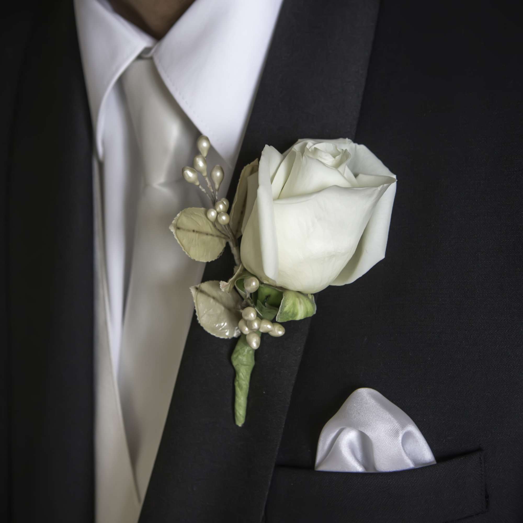 White rose boutonniere on a black suit jacket