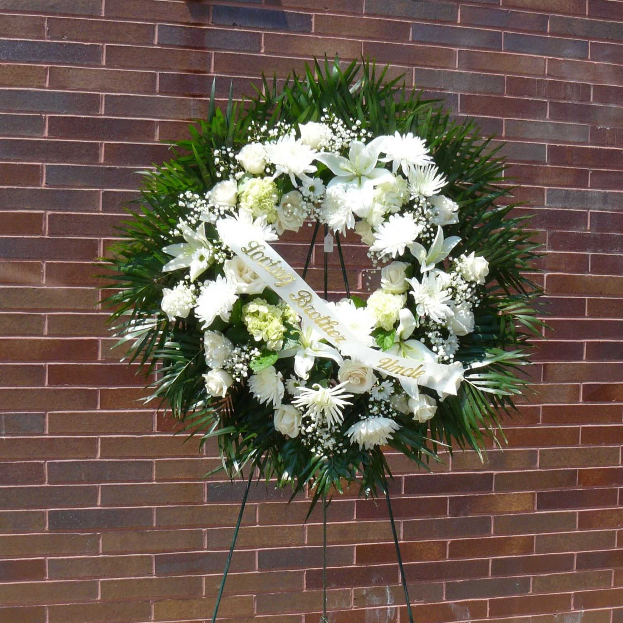 White funeral wreath on a stand with a ribbon