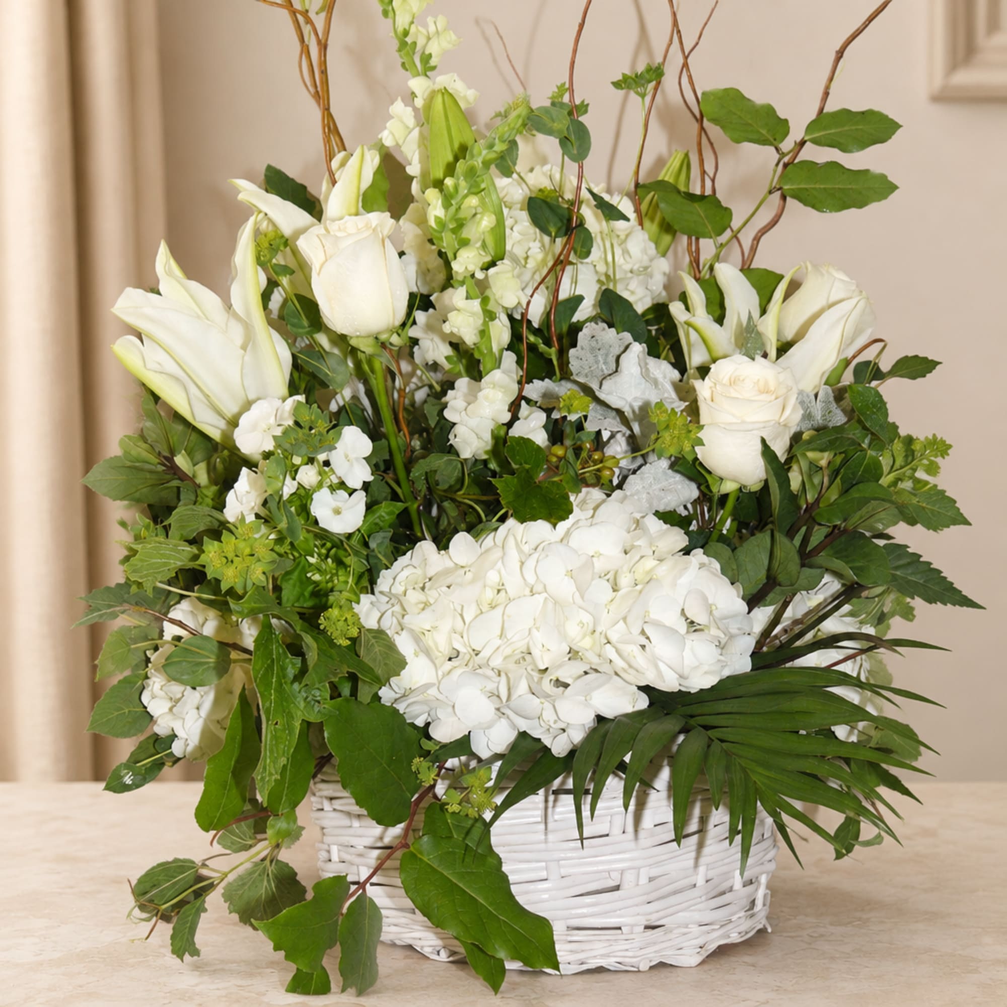 White floral arrangement in a white wicker basket with roses and lilies