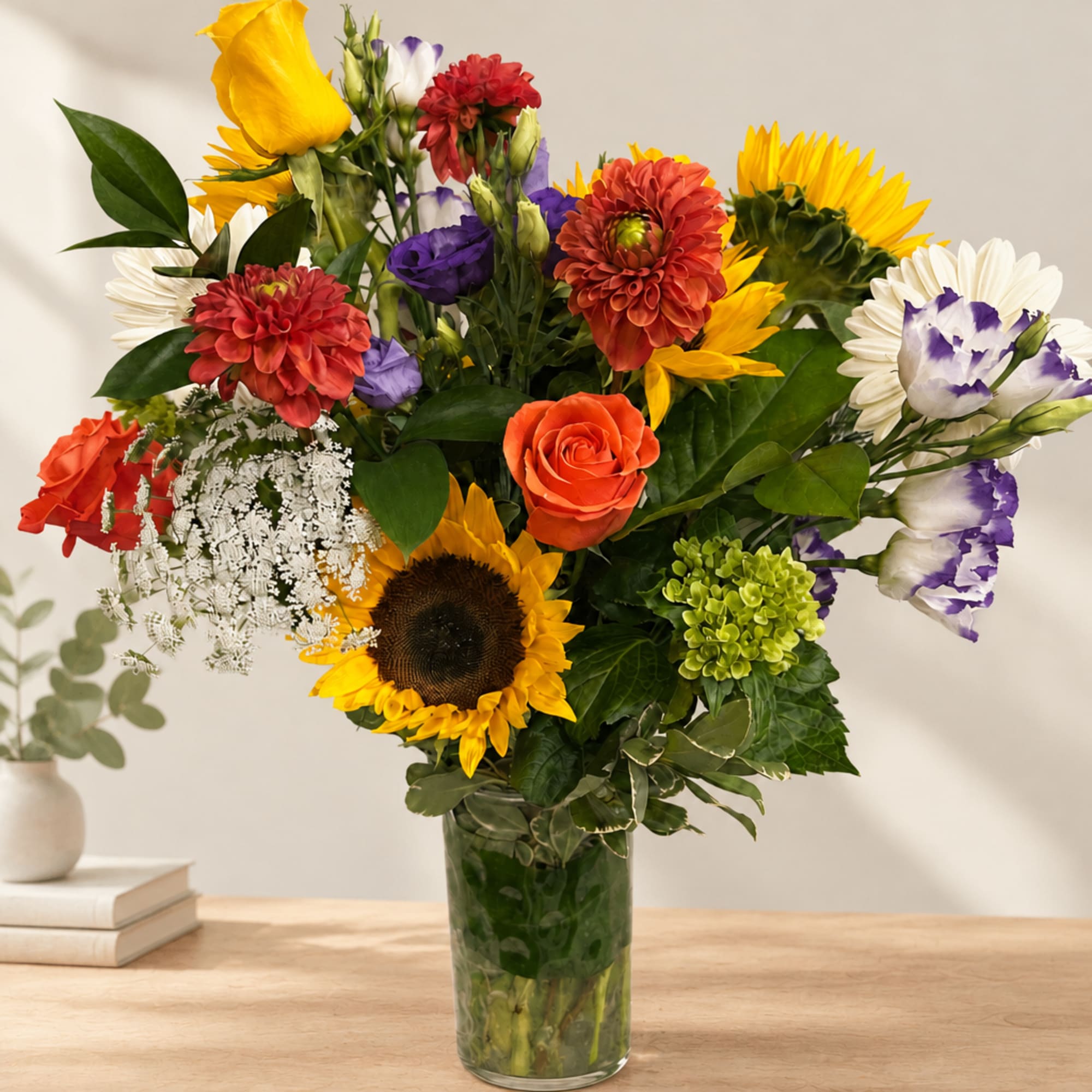 Mixed bouquet with sunflowers, roses, and daisies in a glass vase
