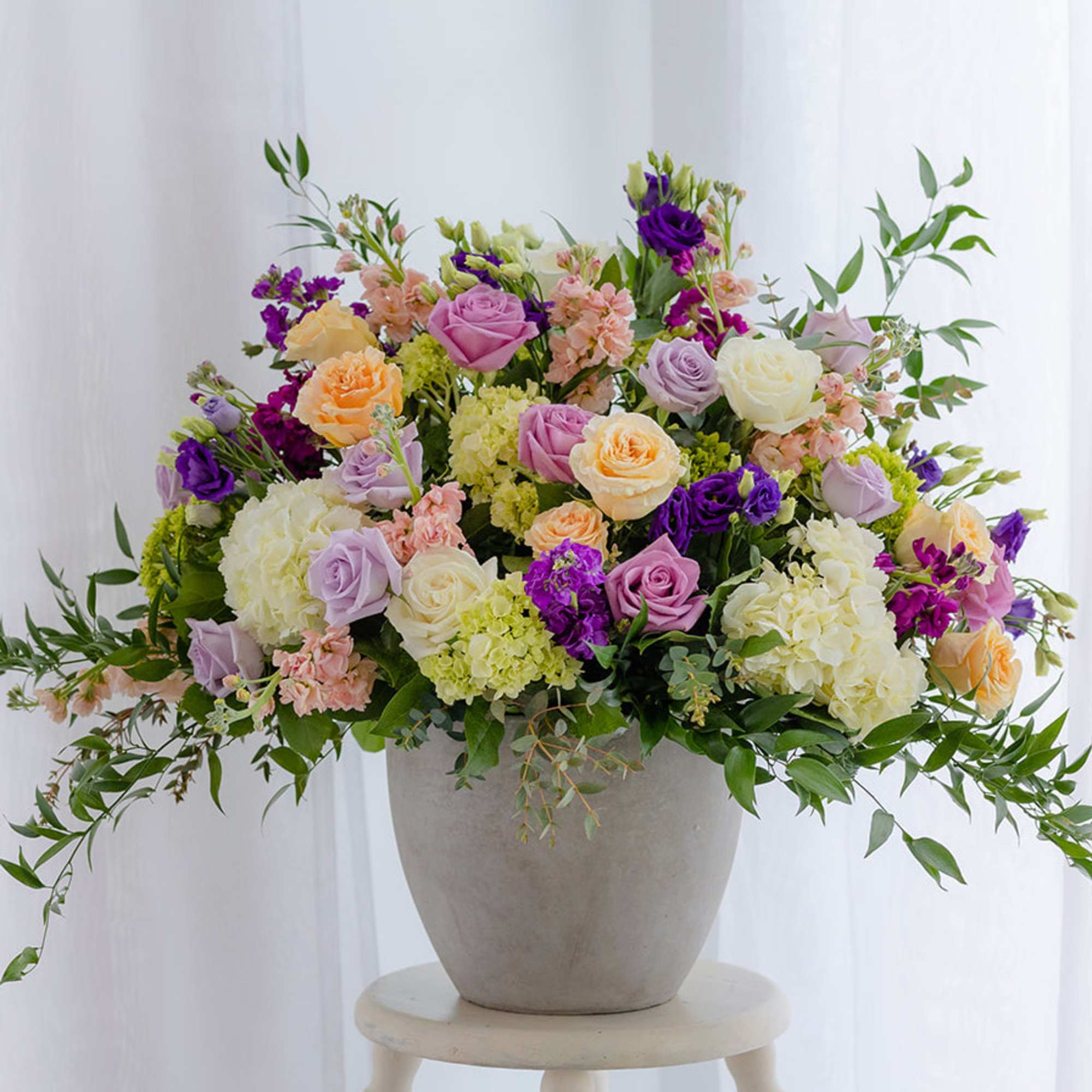 Mixed pastel roses and hydrangeas in a gray vase